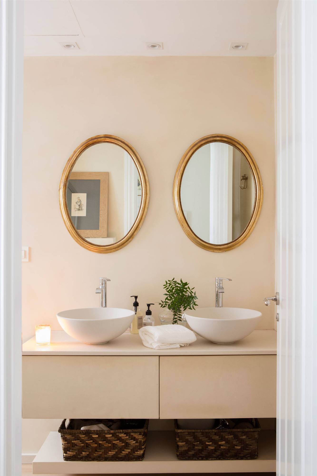 Baño de estilo moderno con espejos redondos con marcos dorados. 