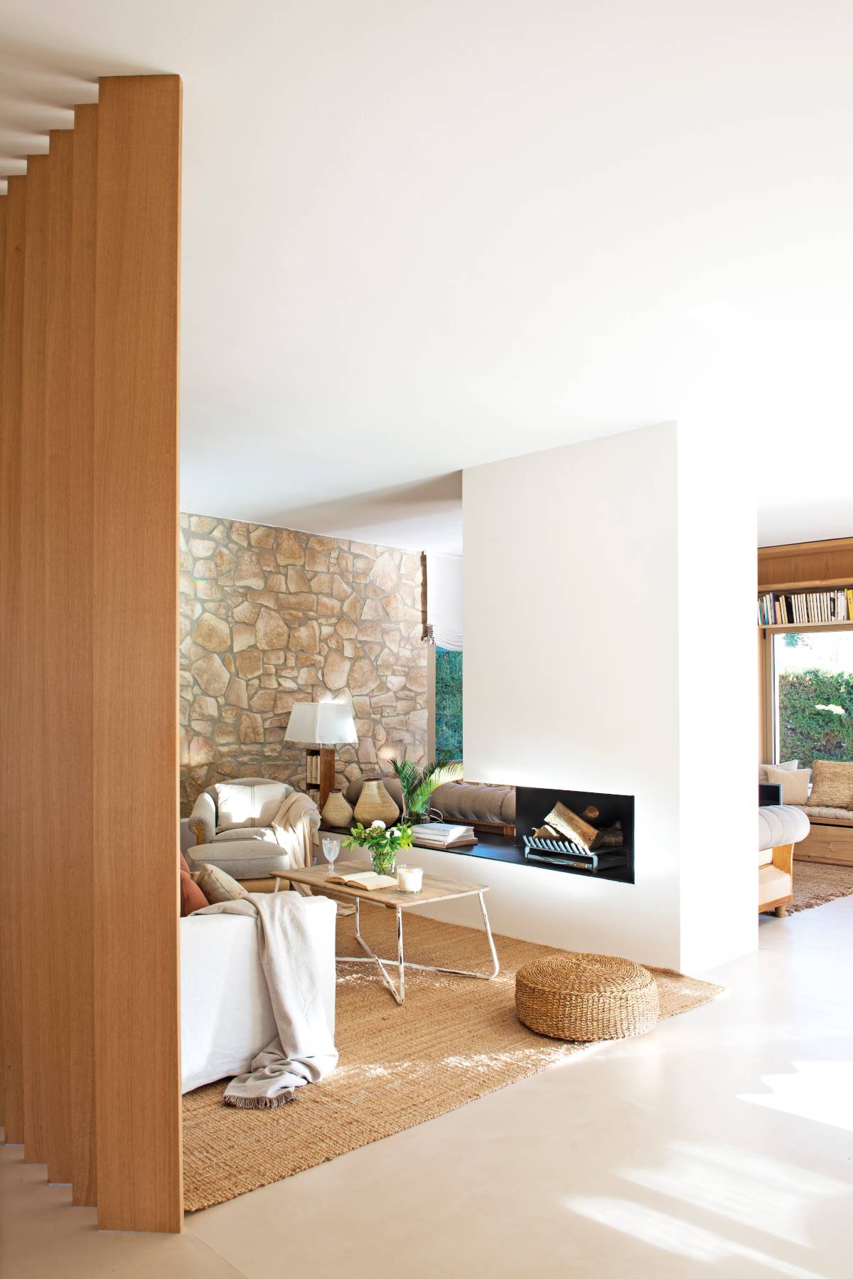 Salón moderno con chimenea que separa en dos zonas el estar. 