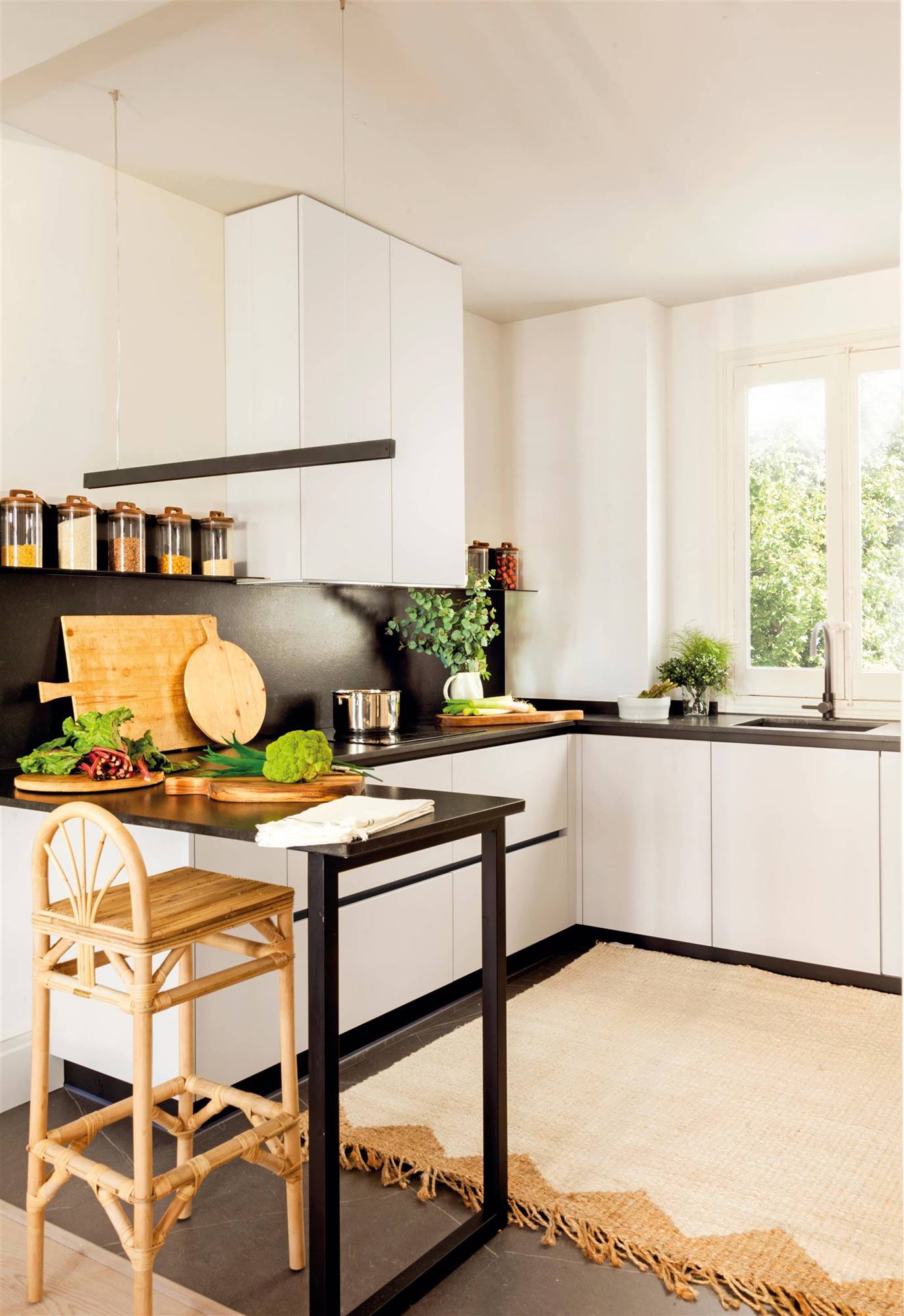 Una cocina pequeña en blanco y negro con una zona de barra muy ligera