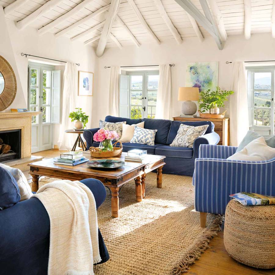 Salón con vigas de madera blancas y sofás azules