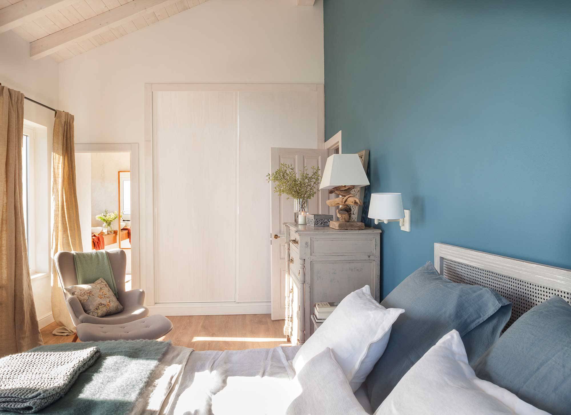 Dormitorio con vigas blancas y pared del cabecero azul