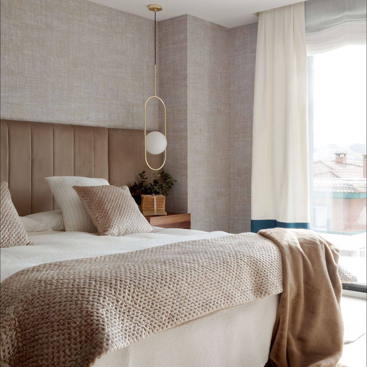 Dormitorio con gran cabecero tapizado en terciopelo
