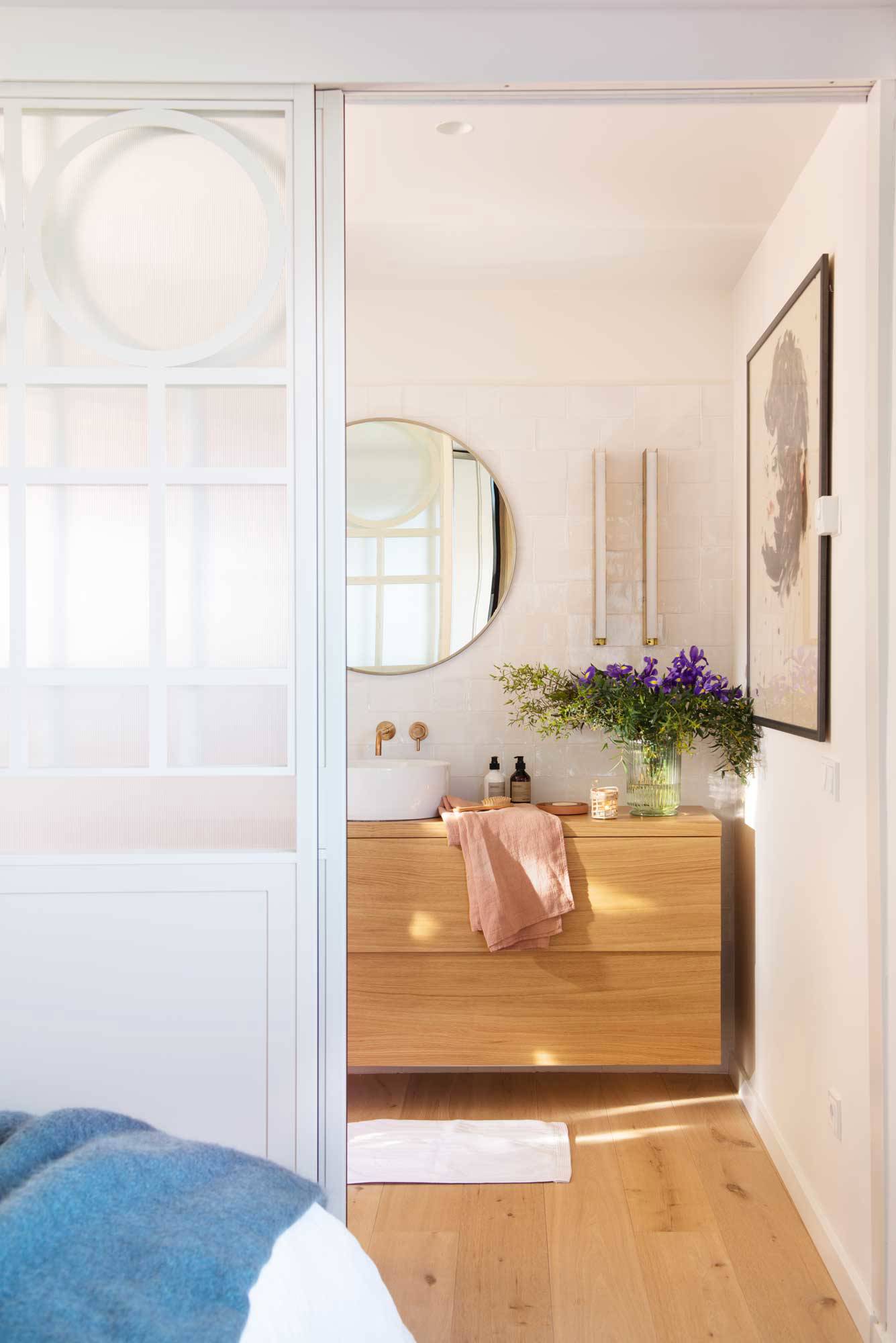 Baño pequeño con puerta corredera blanca y mueble de madera.