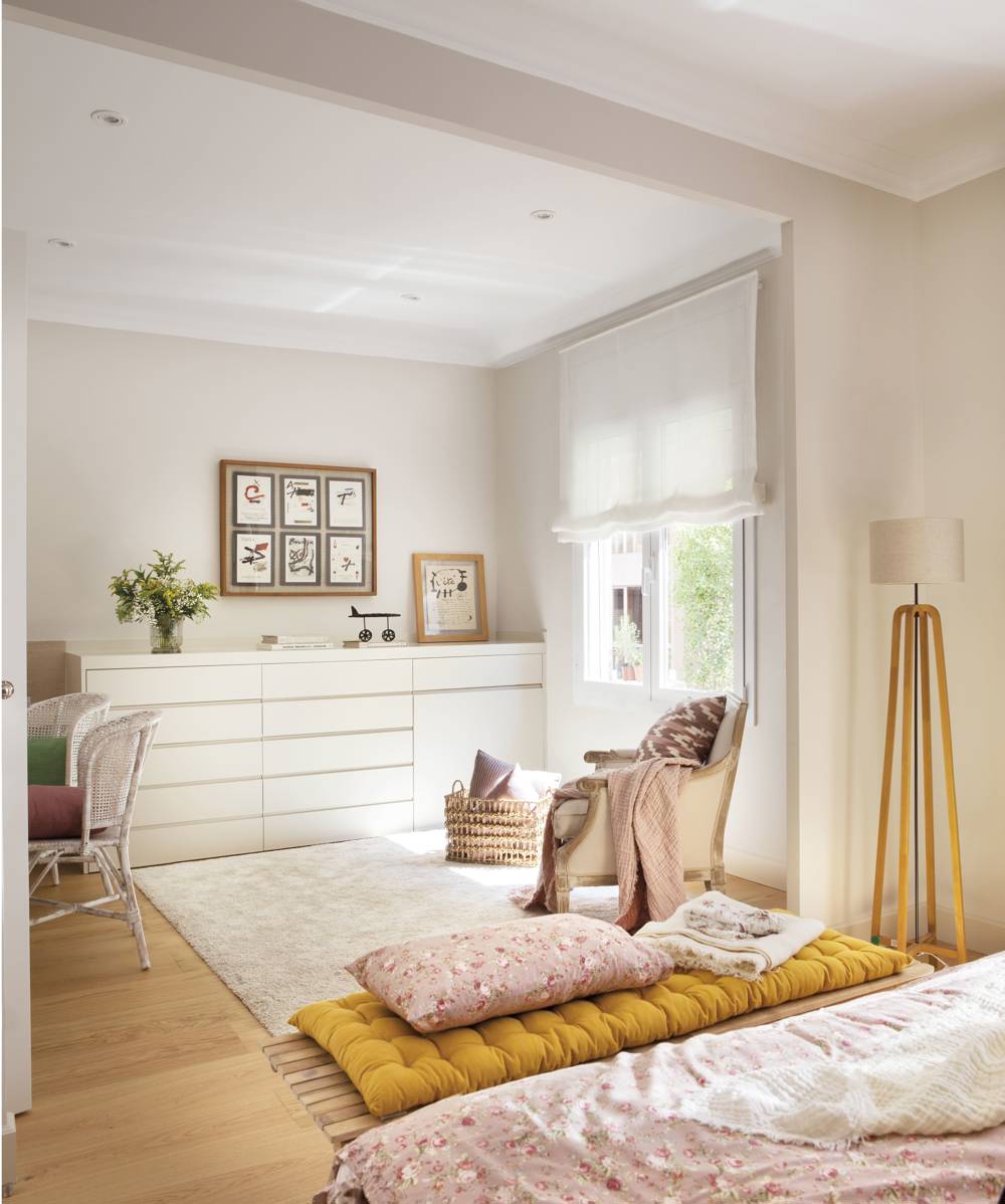 Dormitorio rosa, con banco, cómoda y alfombra de pelo corto. 