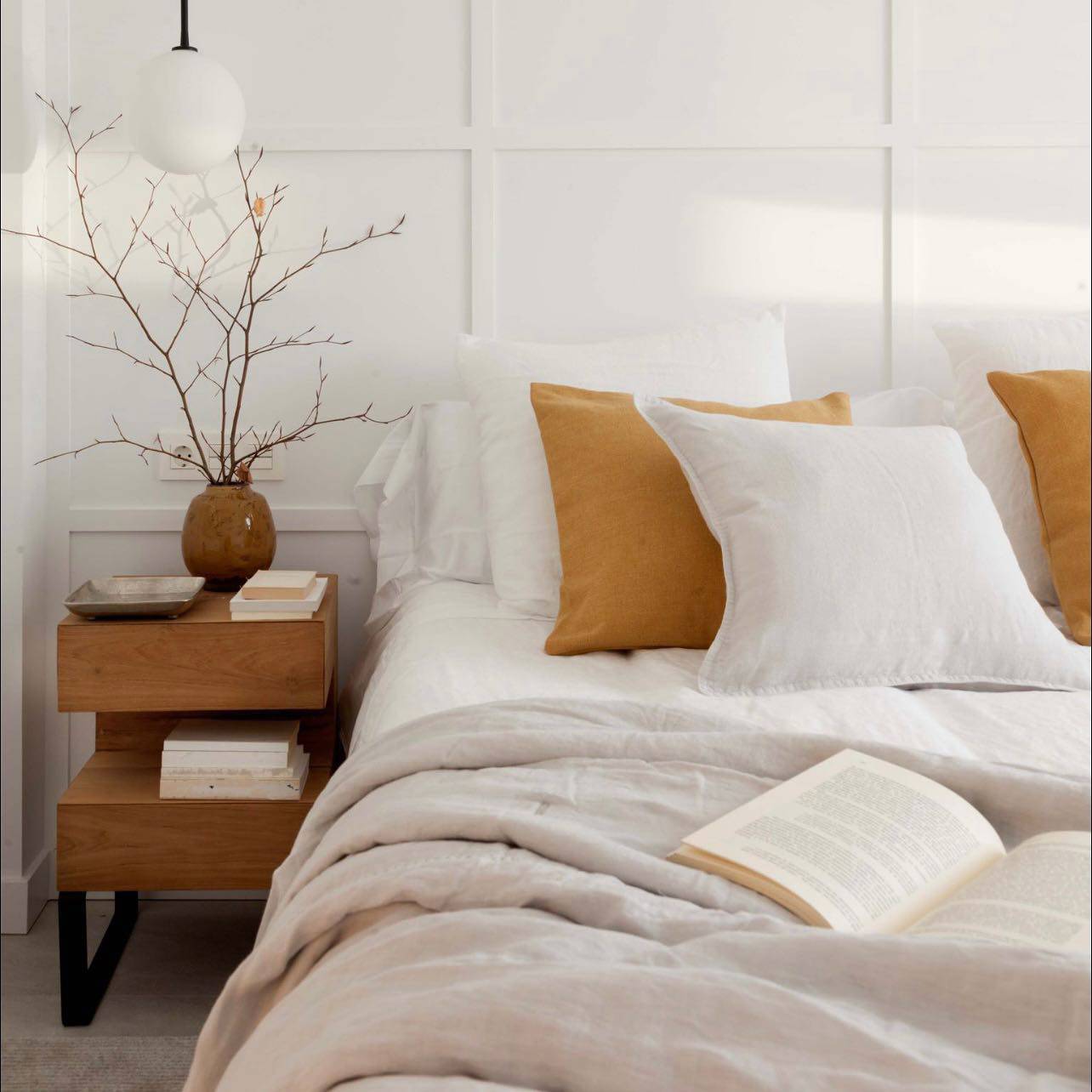 Dormitorio blanco con pared empanelada y mesita de madera