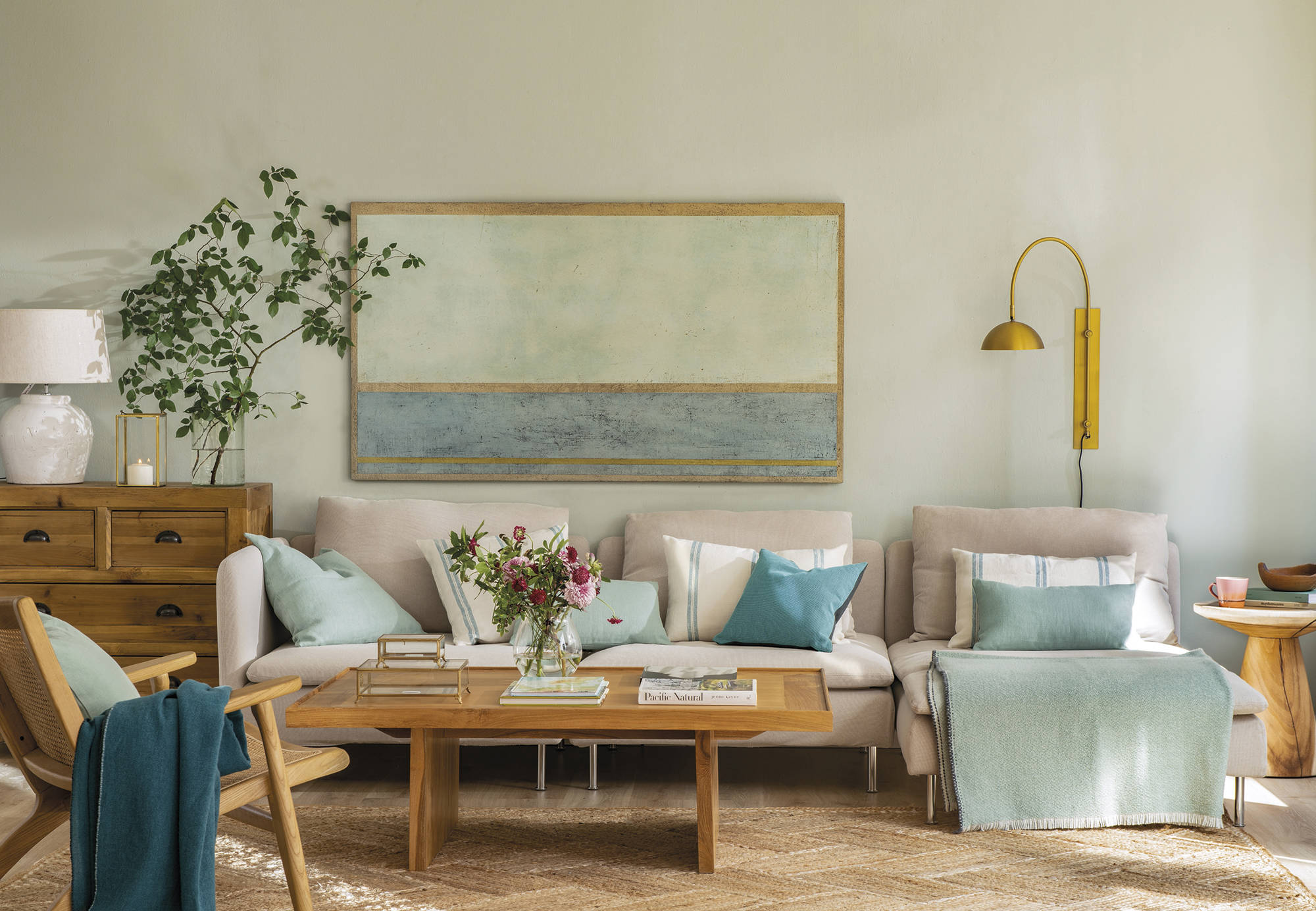 Salón  con sofá blanco, muebles de madera y cojines en verde mint y azul