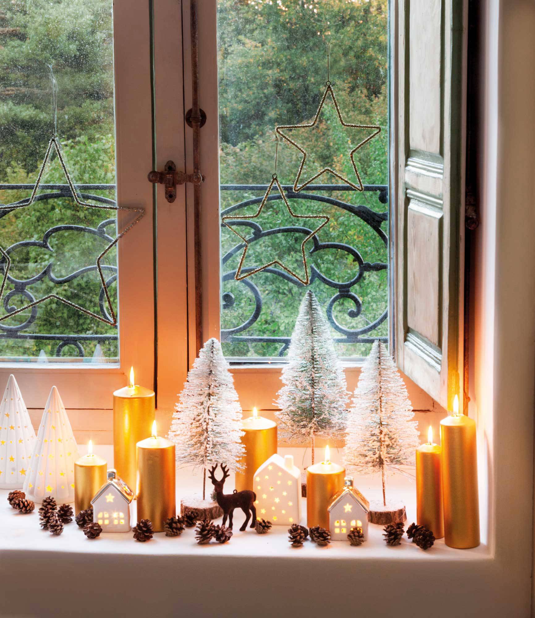Ventana decorada con mini árboles de Navidad, figuras y velas