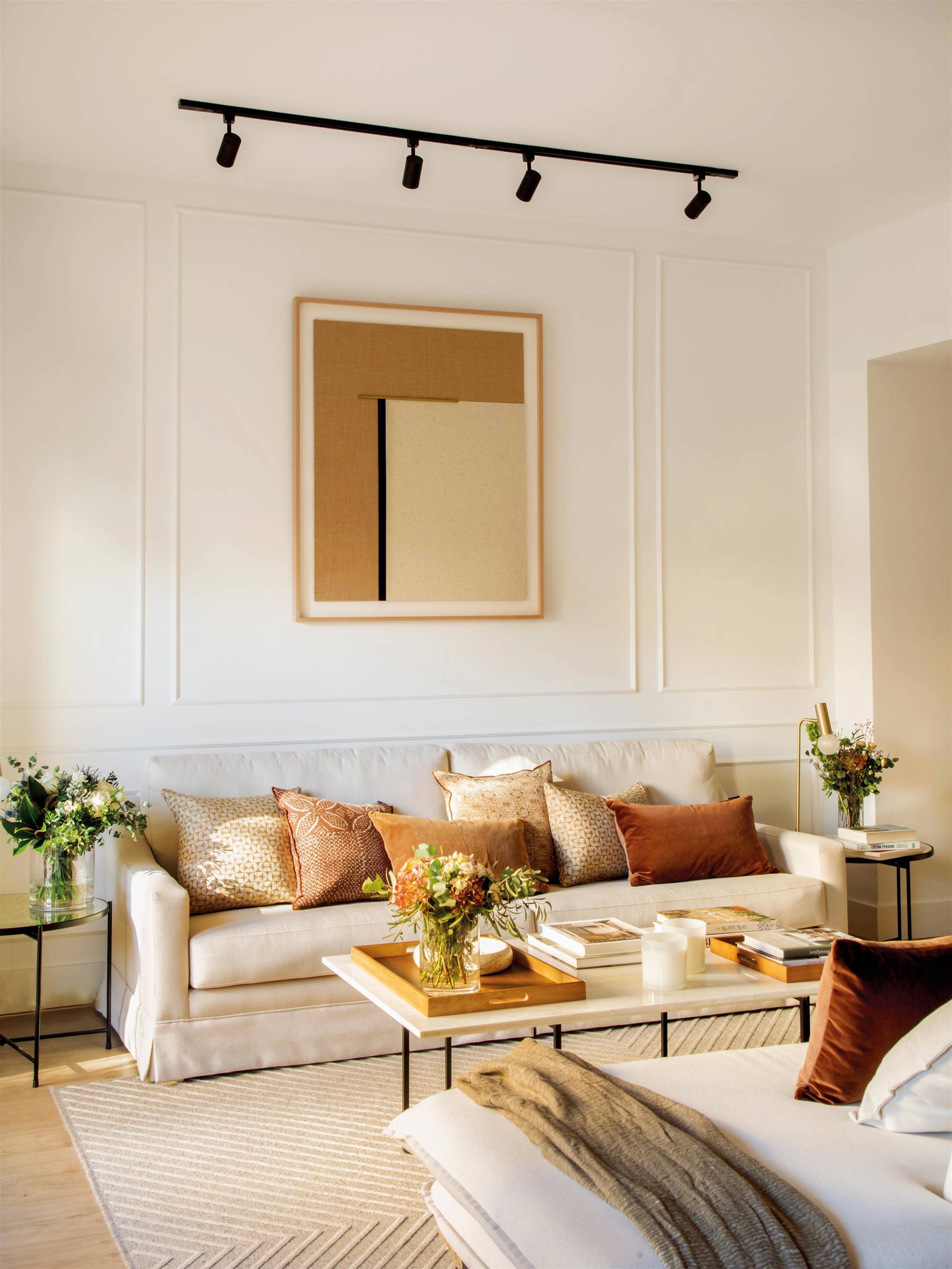Salón con sofá, molduras en pared y cuadro con iluminación.