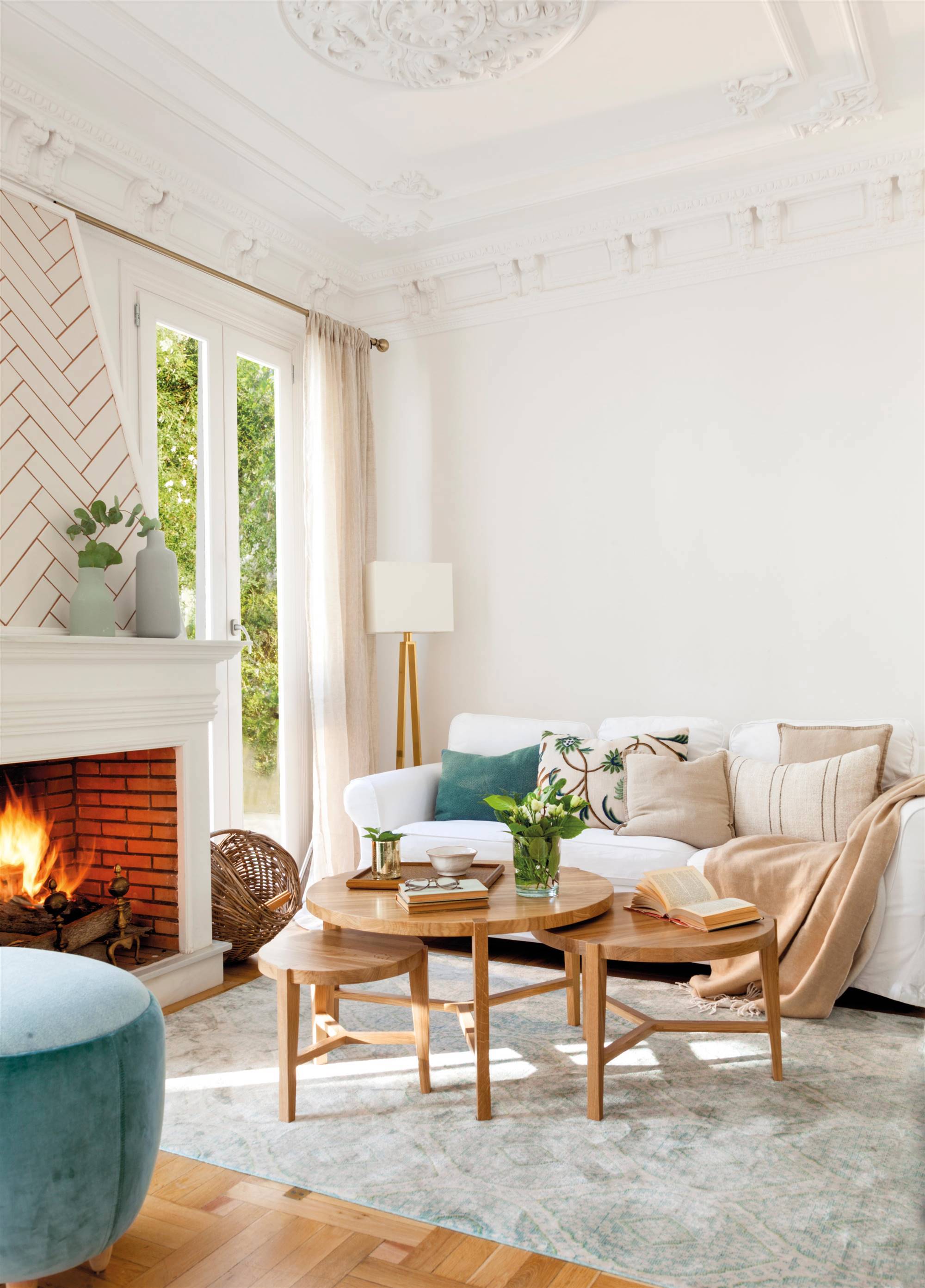 Salón con molduras en el techo, chimenea revestida con azulejos y sofá blanco. 