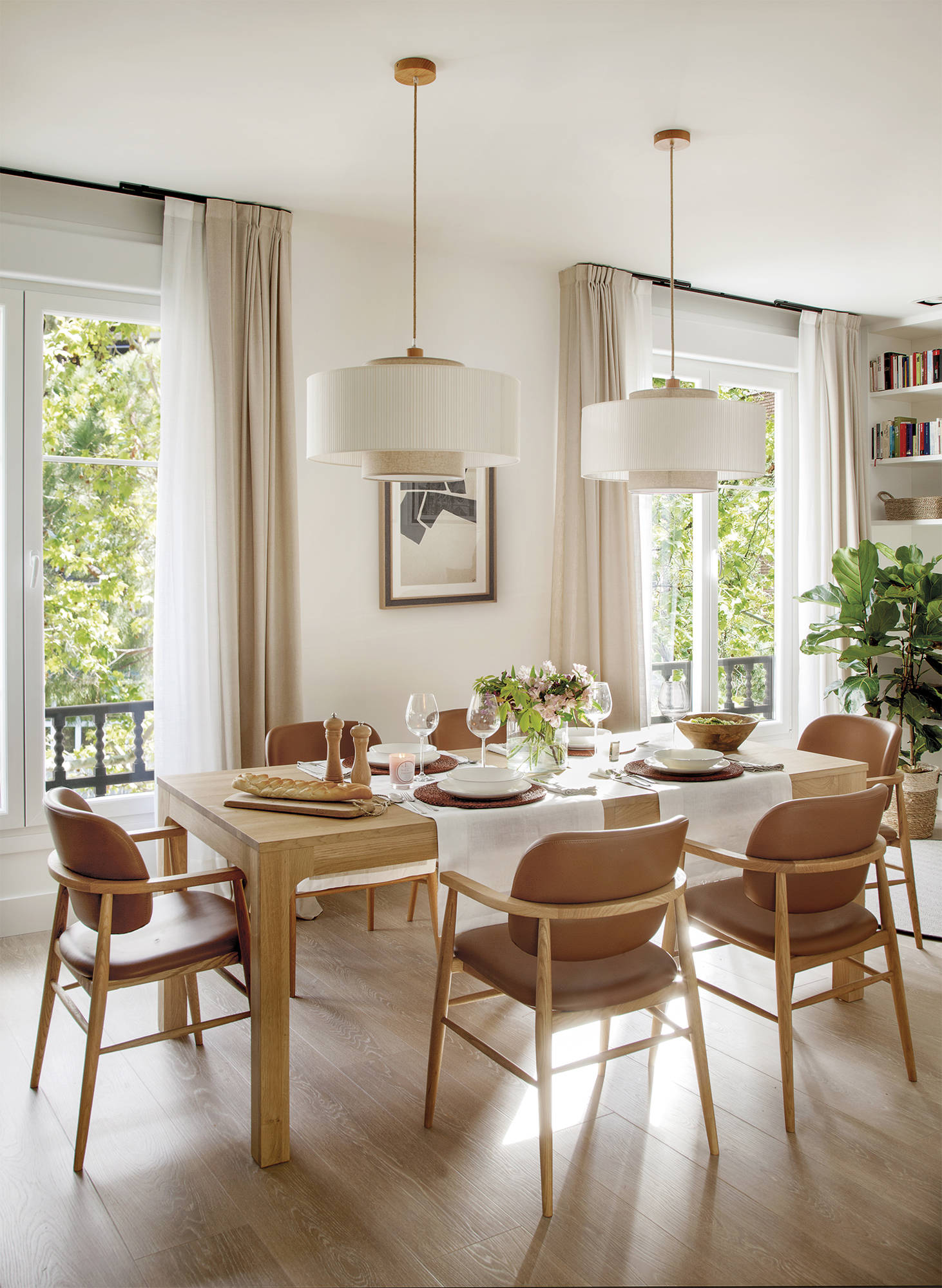 Comedor con mesa de madera, sillas de cuero, lámparas de techo grandes y modernas. 