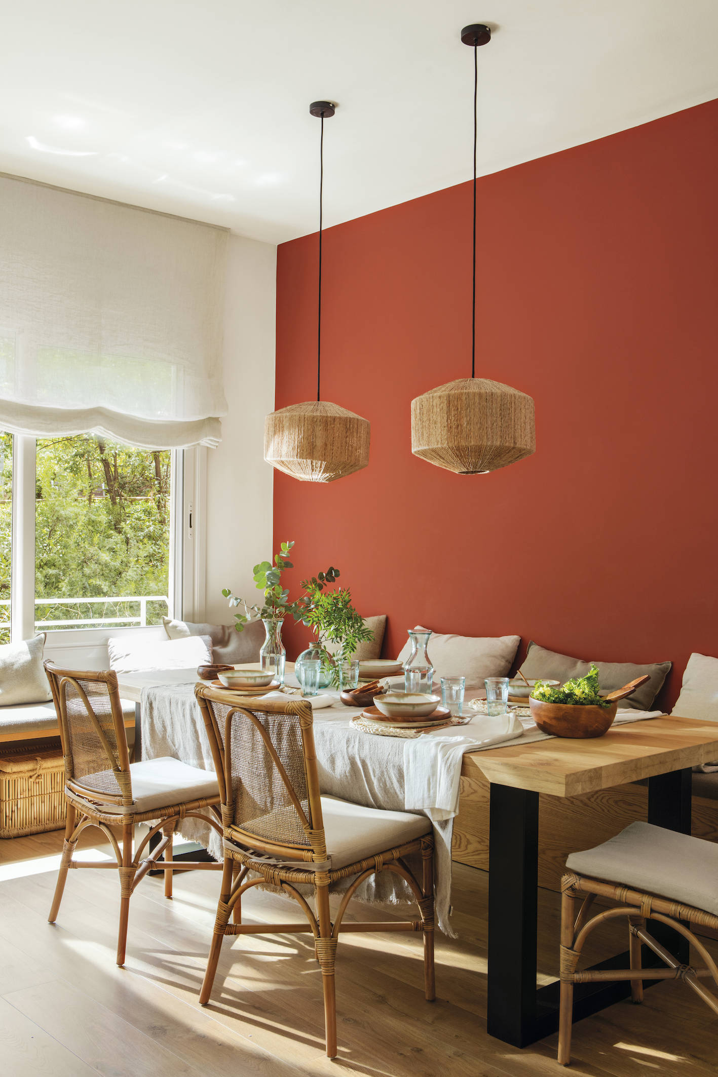 Comedor con pared frontal en tonos rojos y una gran mesa realizada a medida en madera y hierro. 