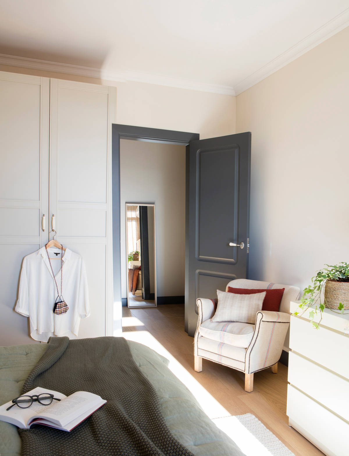 Dormitorio con cómoda blanca modelo Malm y butaca tapizada. 