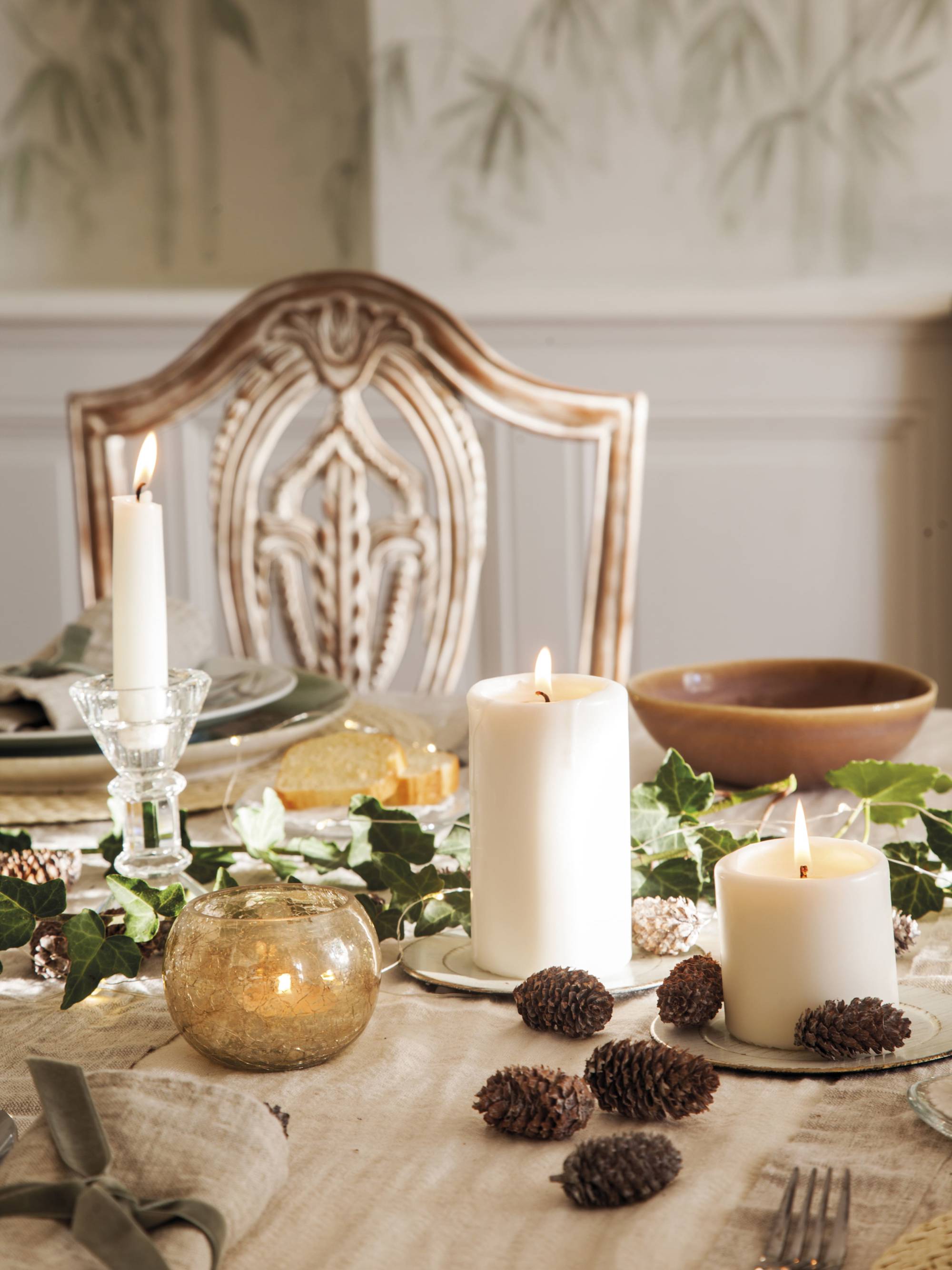 Comedor con mesa de Navidad decorada con velas y piñas.