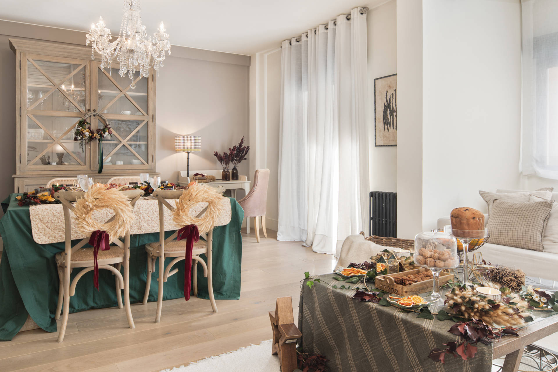 Salón comedor con decoración navideña con coronas, manteles verdes y centros de mesa festivos.