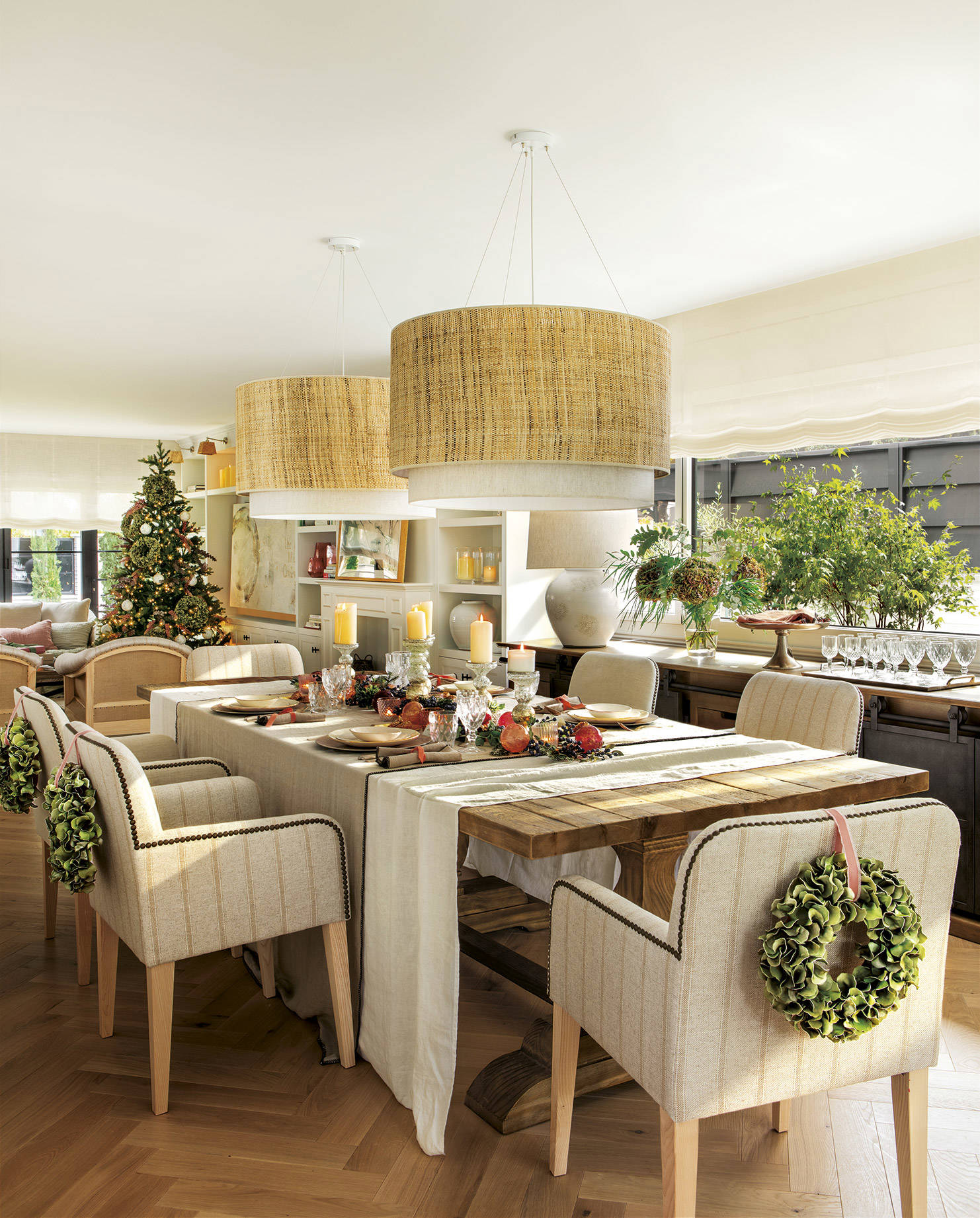 Comedor clásico con mesa de madera y sillas tapizadas decoradas con una corona de Navidad. 