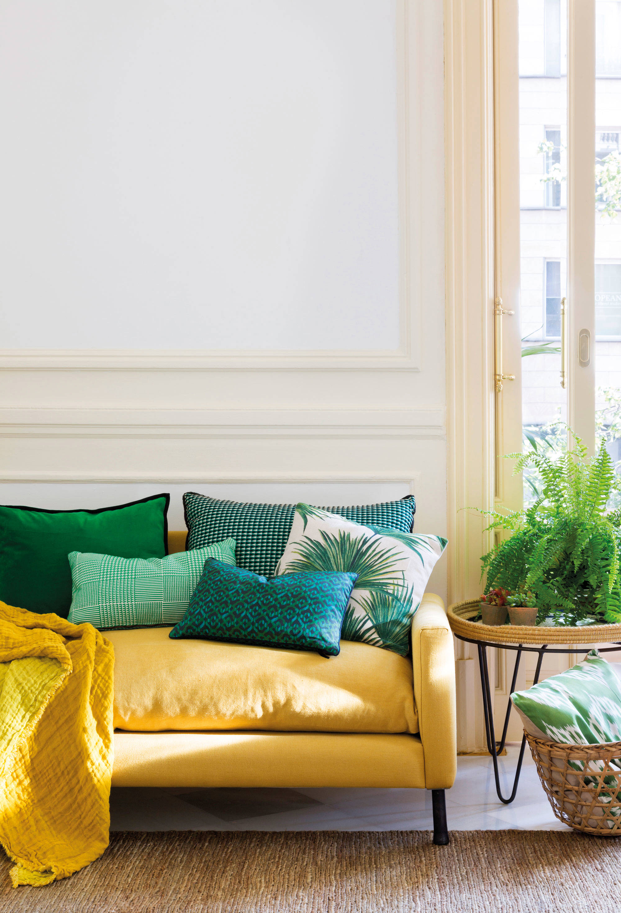 Salón con sofá amarillo atemporal y cojines con estampados azules y verdes. 