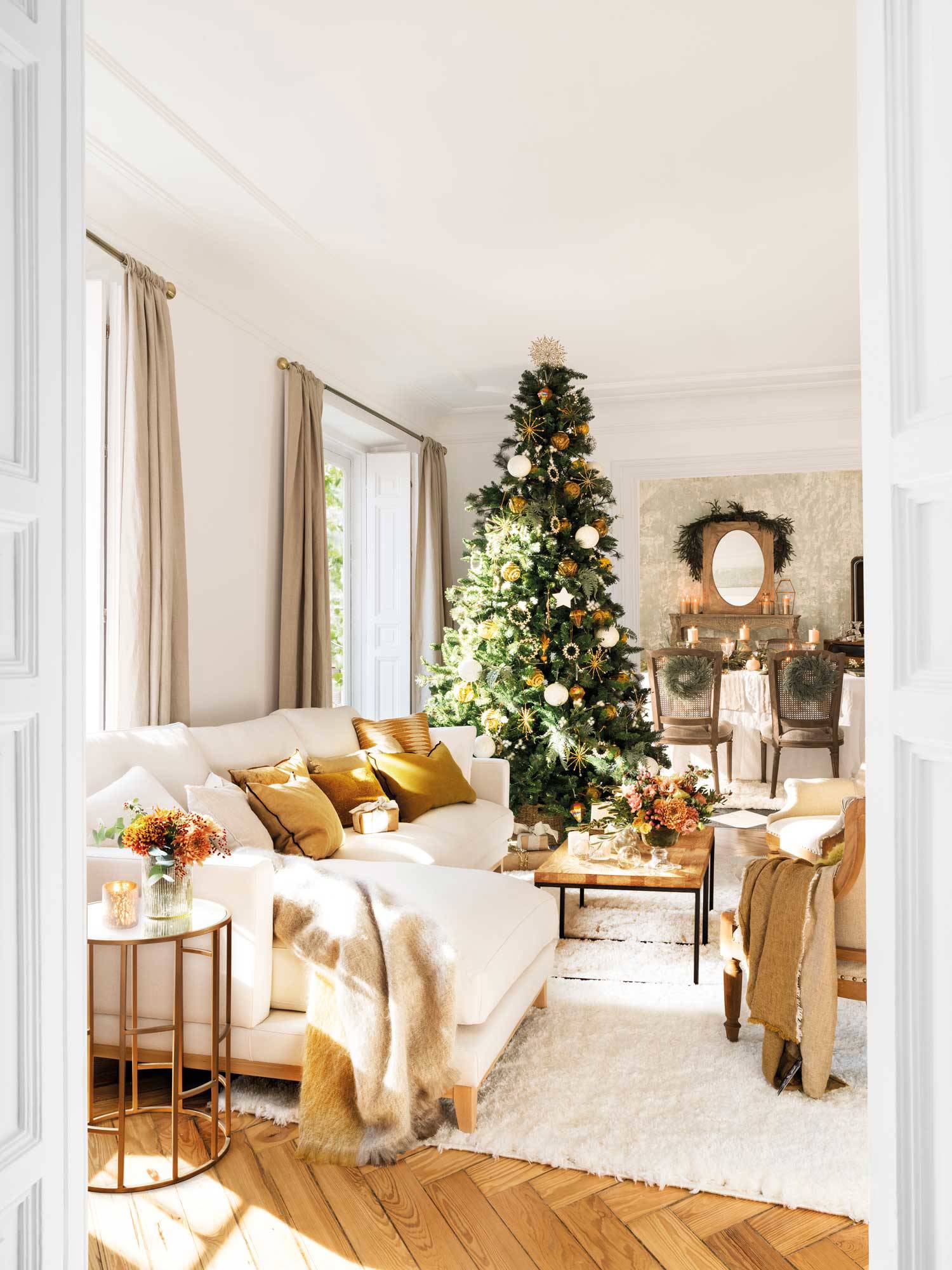 Salón navideño con sofá blanco con chaise longue, árbol de Navidad y cojines mostaza.