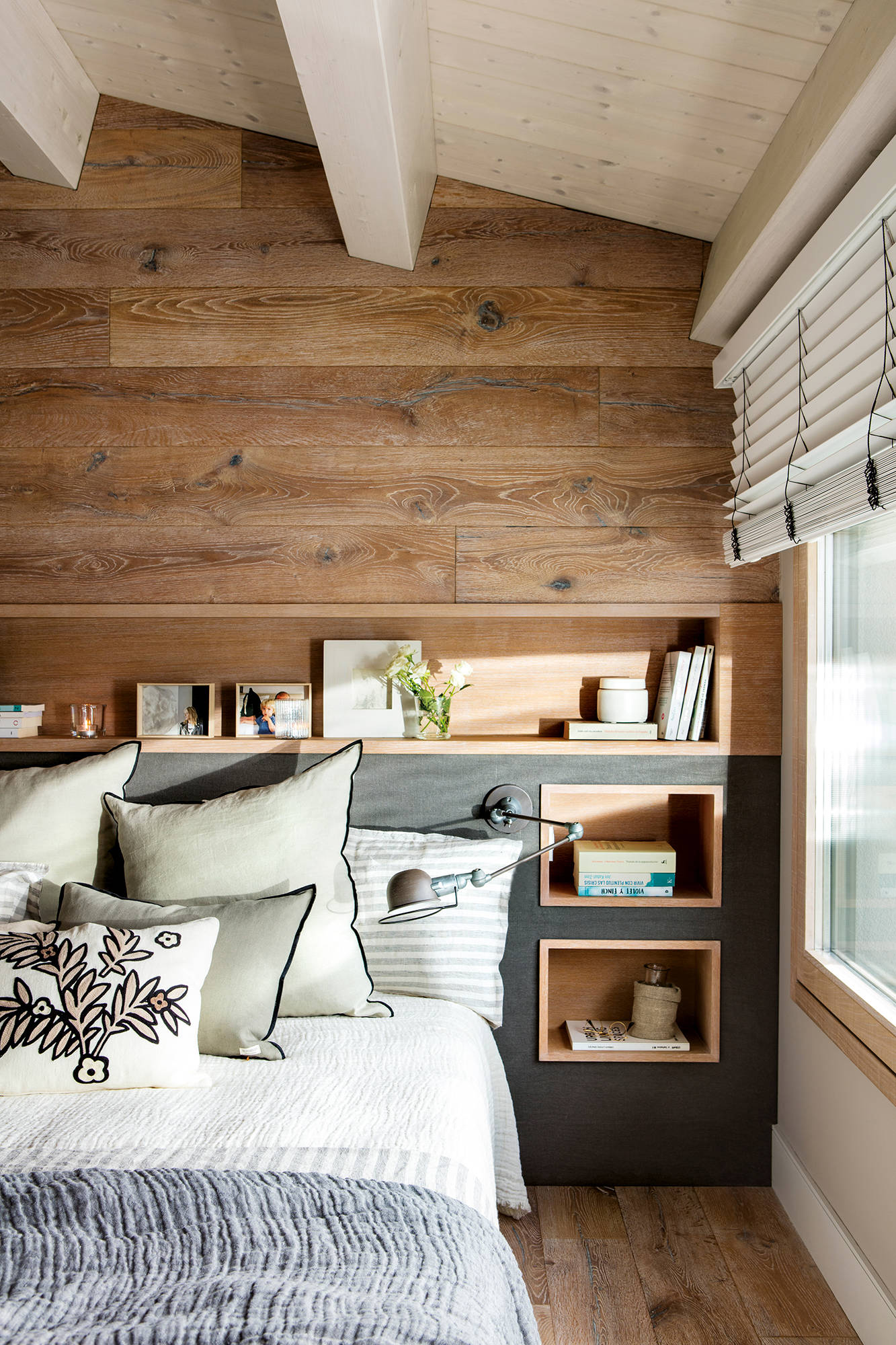 Dormitorio con pared revestida de madera y cabecero tipo hornacina y mesillas incorporadas
