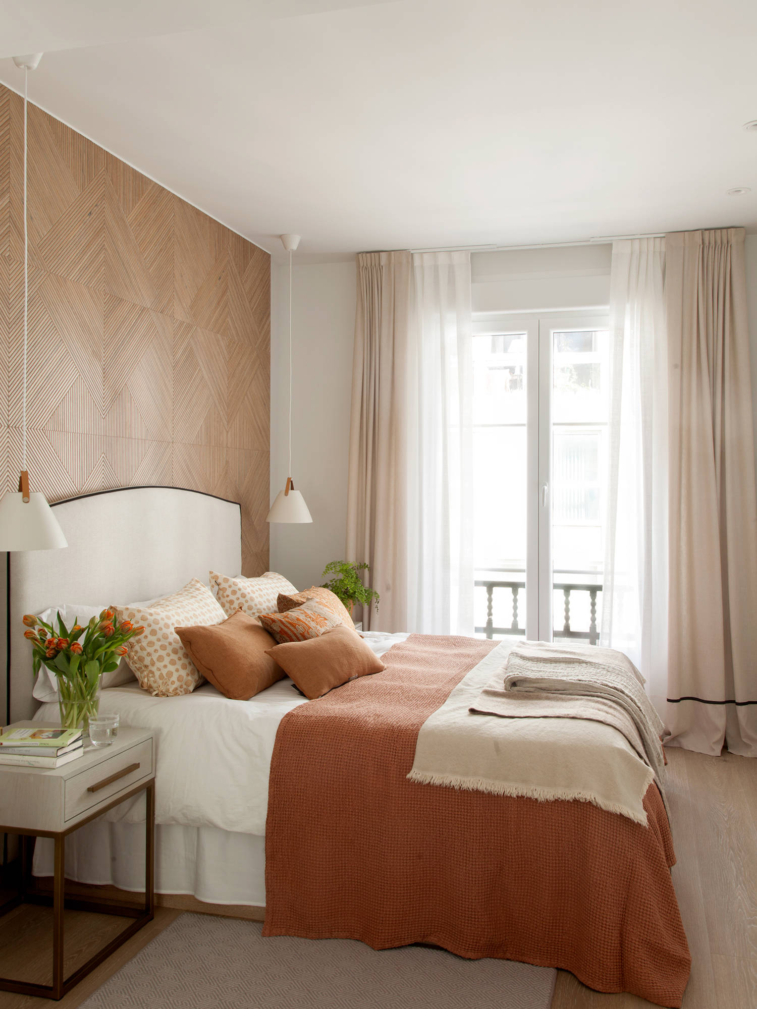 Dormitorio romántico con pared revestida de microcemento y ropa de cama rosa y blanca. 
