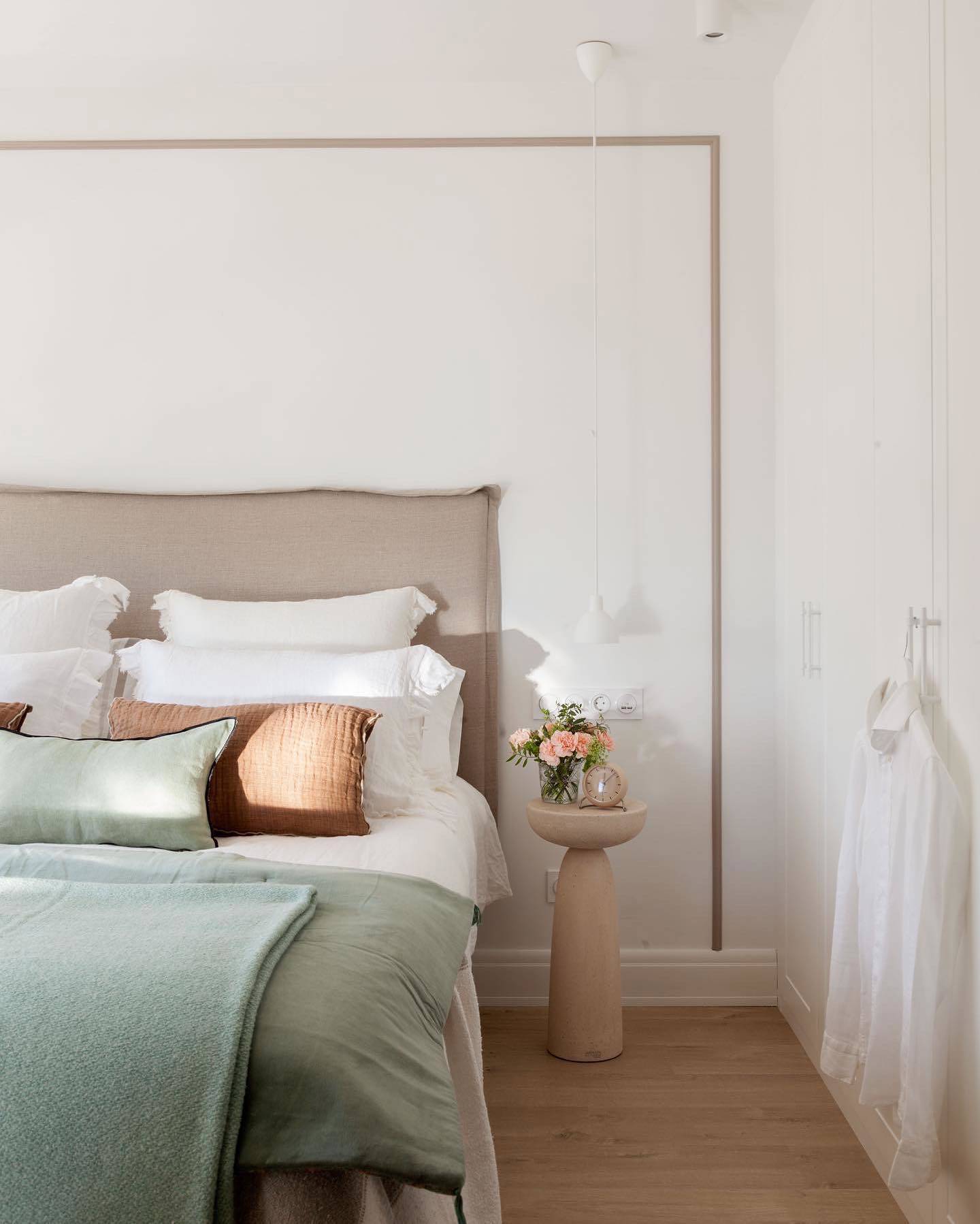 Dormitorio con cabecero tapizado y moldura decorativa en la pared. 