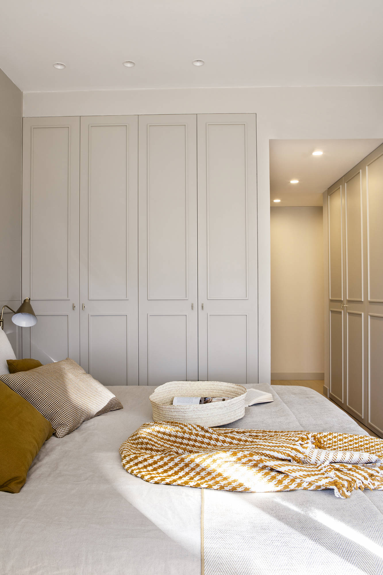Dormitorio con vestidor con armarios blancos con molduras. 