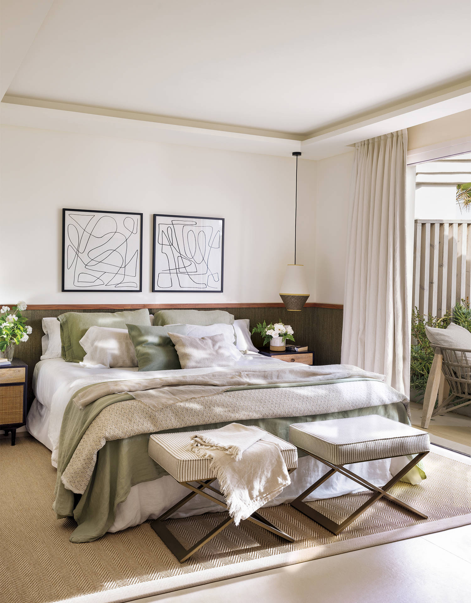 Dormitorio principal con ropa de cama verde, arrimadero como cabecero y asientos al pie de la cama