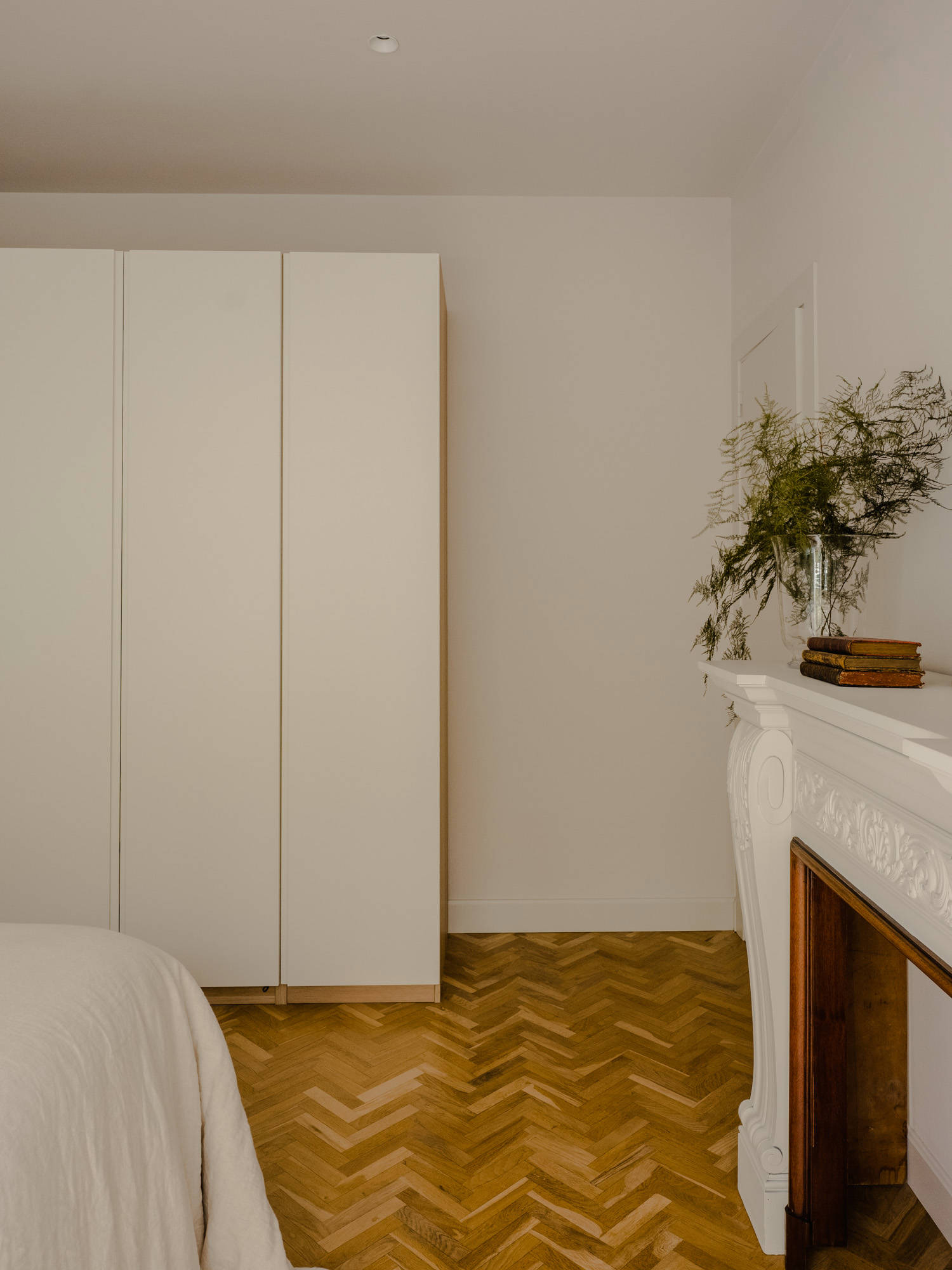 Dormitorio con suelo en espiga, chimenea y armarios blancos Elena Eyre