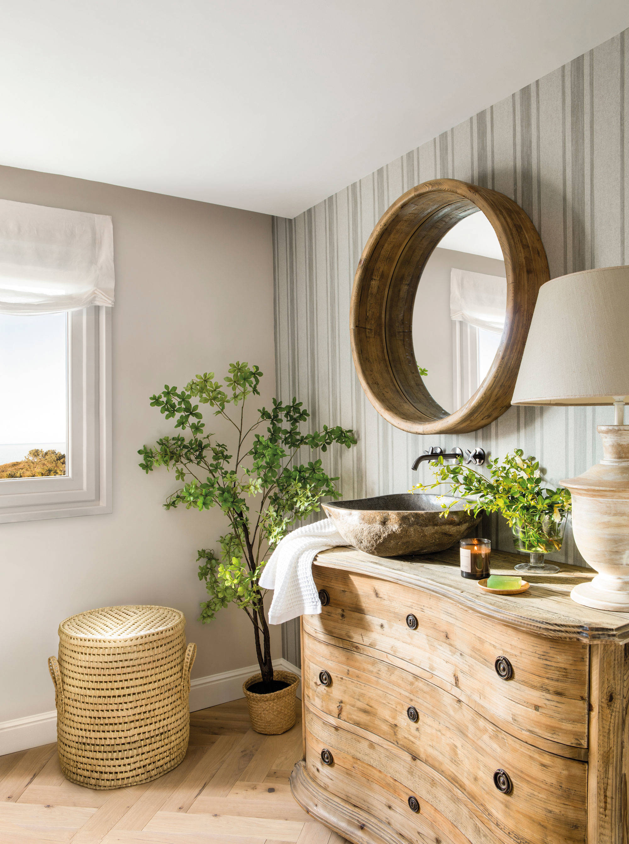 Baño de estilo rústico con mueble de madera y espejo redondo. 