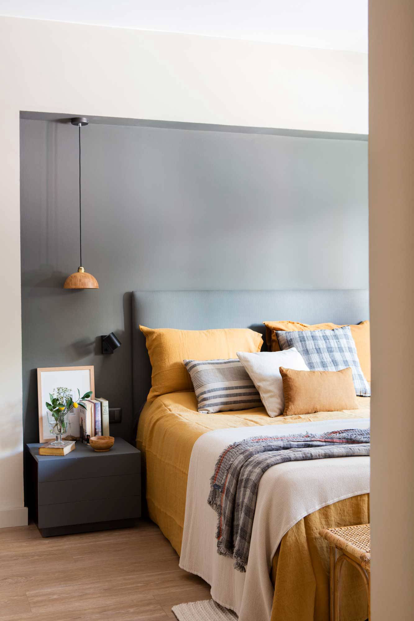 Dormitorio con pared en gris oscuro y ropa de cama mostaza. 