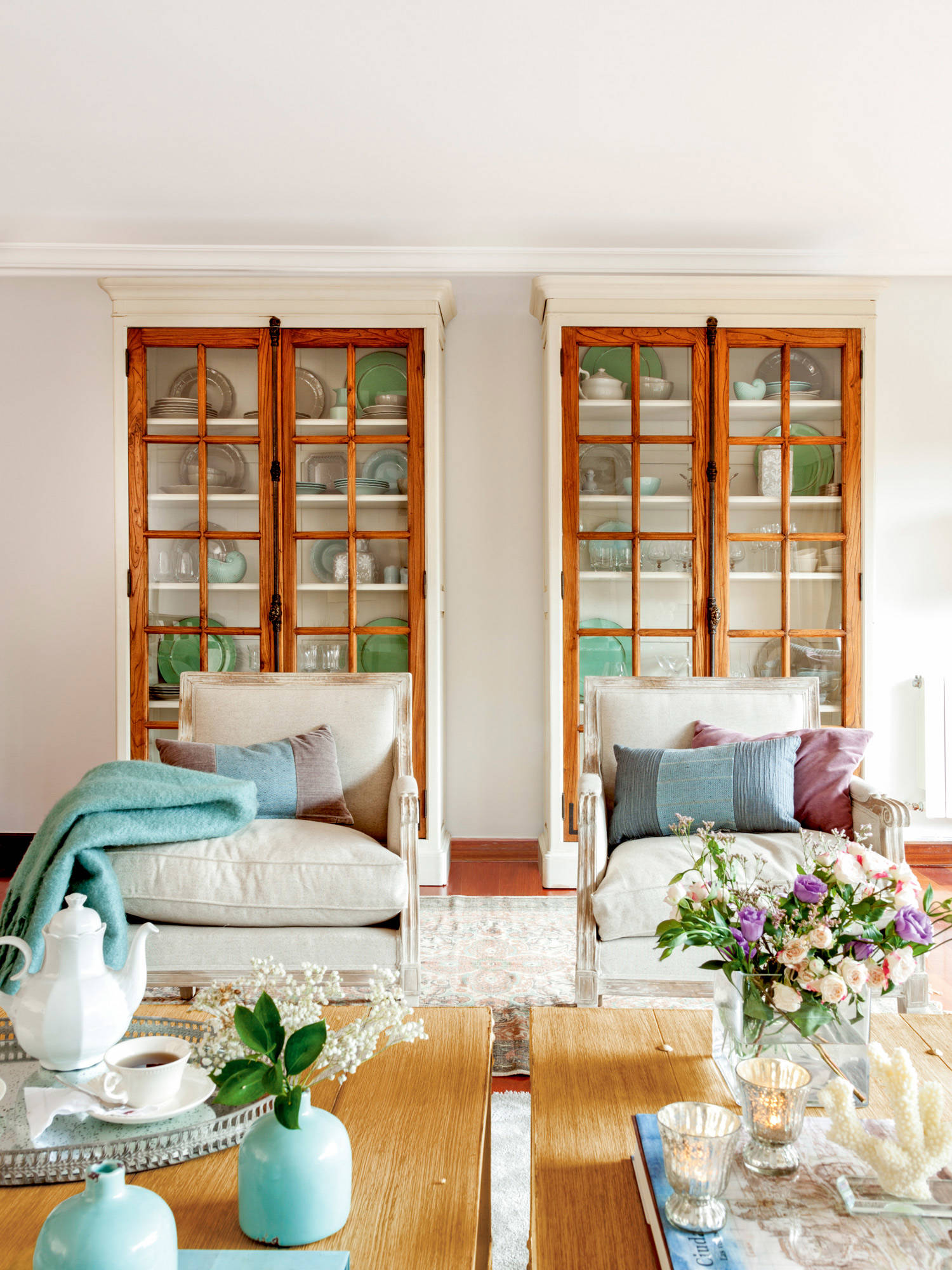 Salón con vitrinas gemelas de madera y butacas blancos.