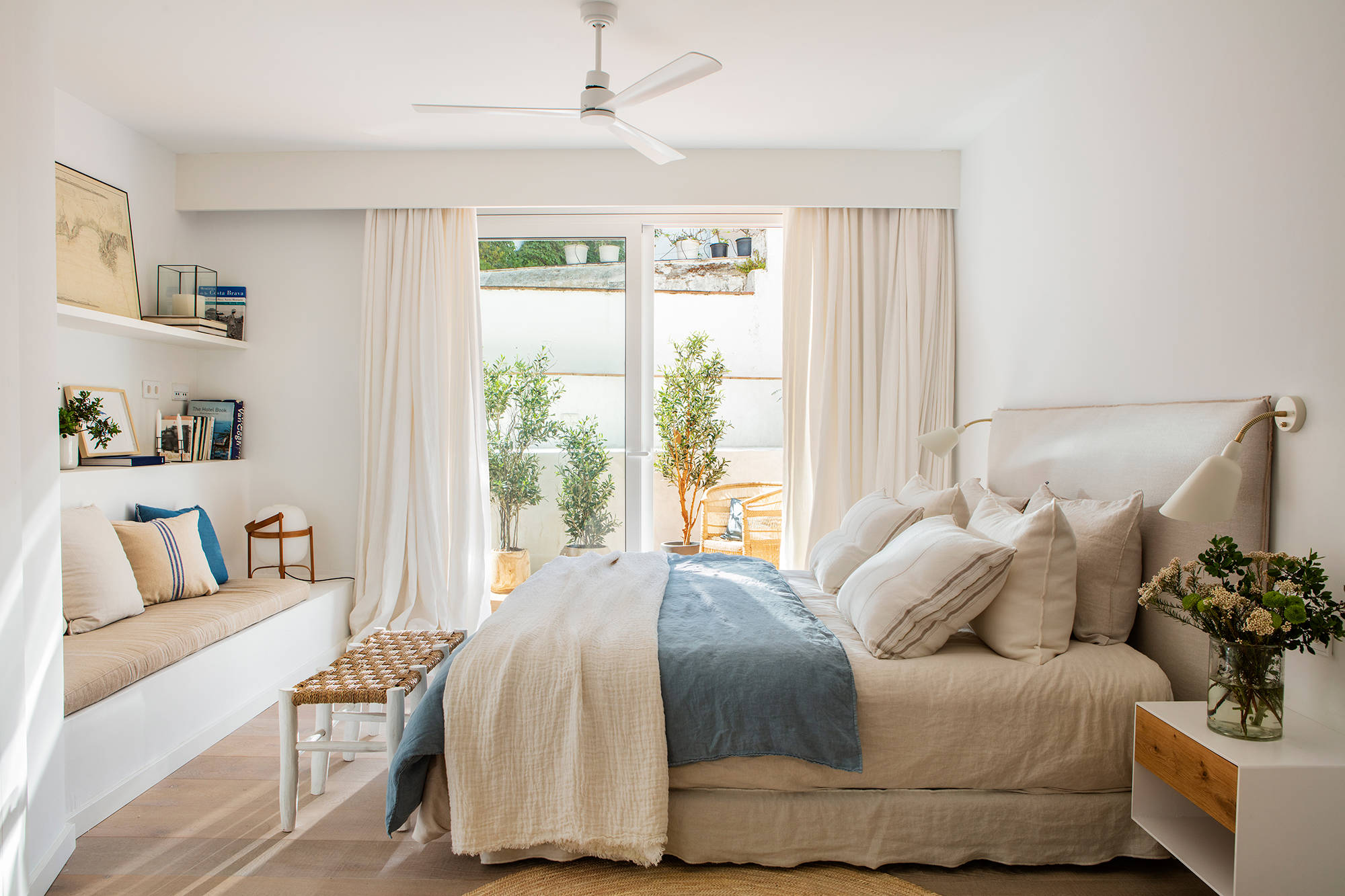 Dormitorio primaveral con base blanca, muebles a medida y ropa de cama azul.