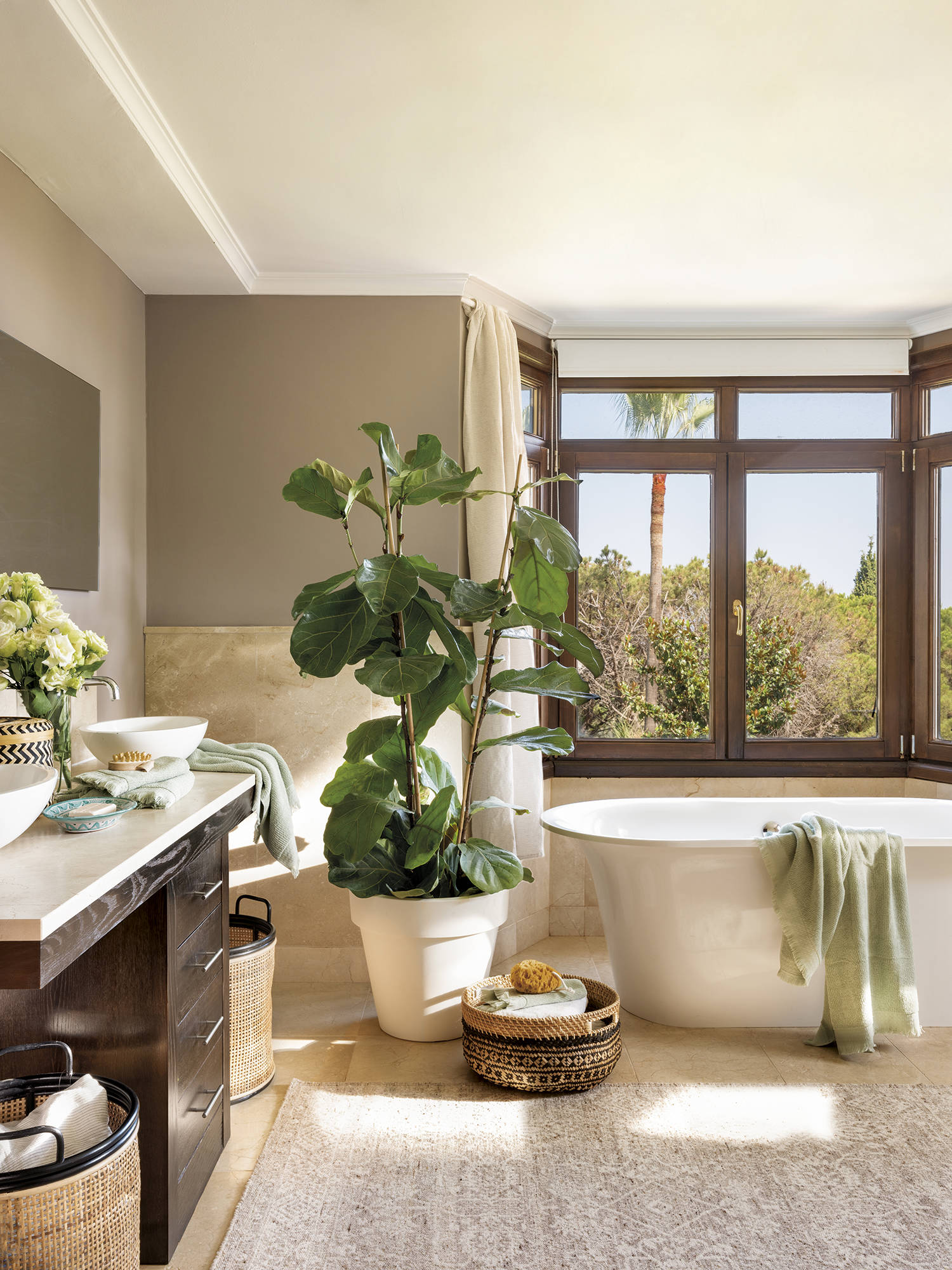 Baño con bañera exenta, mueble bajolavabo de madera y alfombra. 