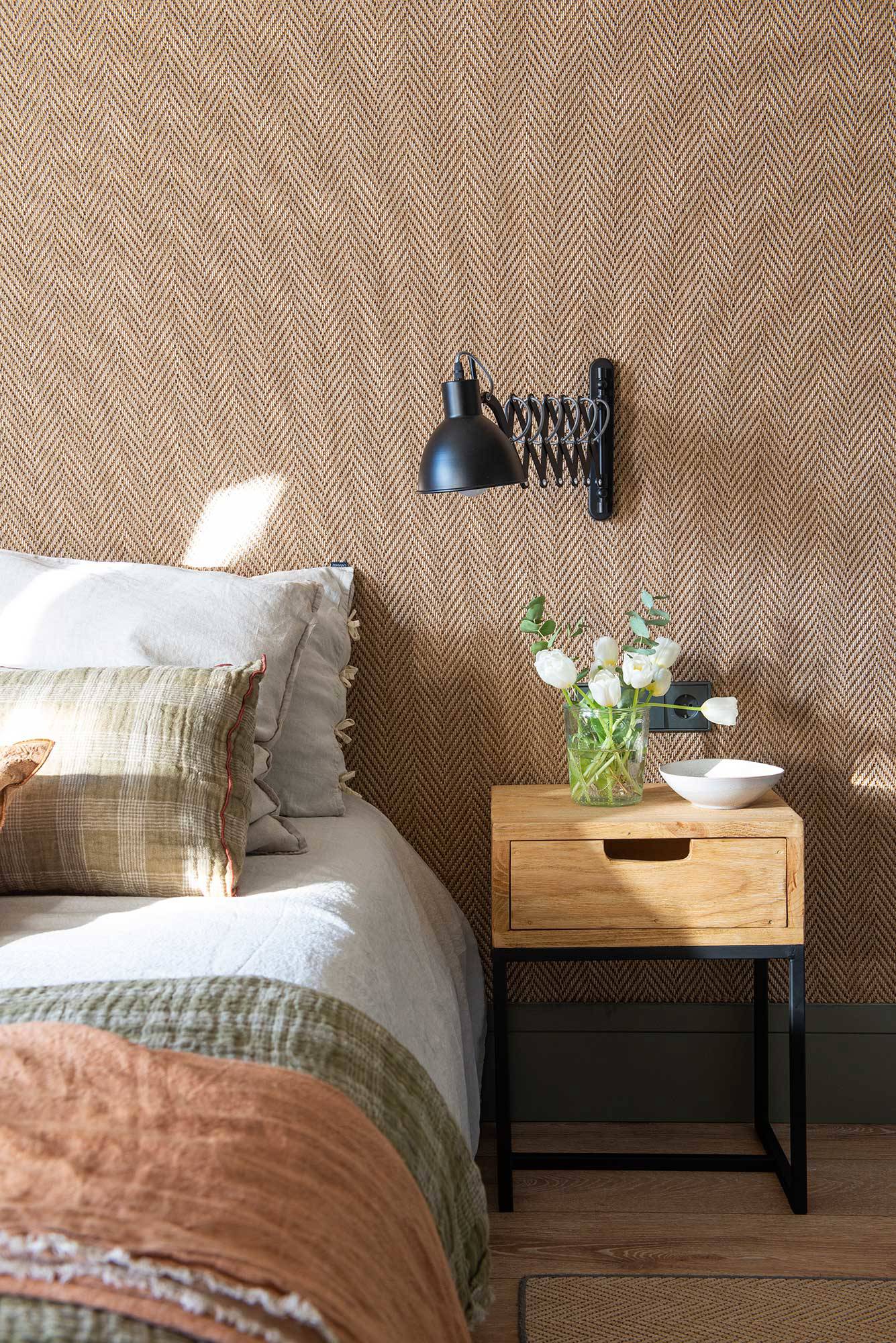 Dormitorio con pared revestida de tejido de moqueta y zócalo oscuro. 