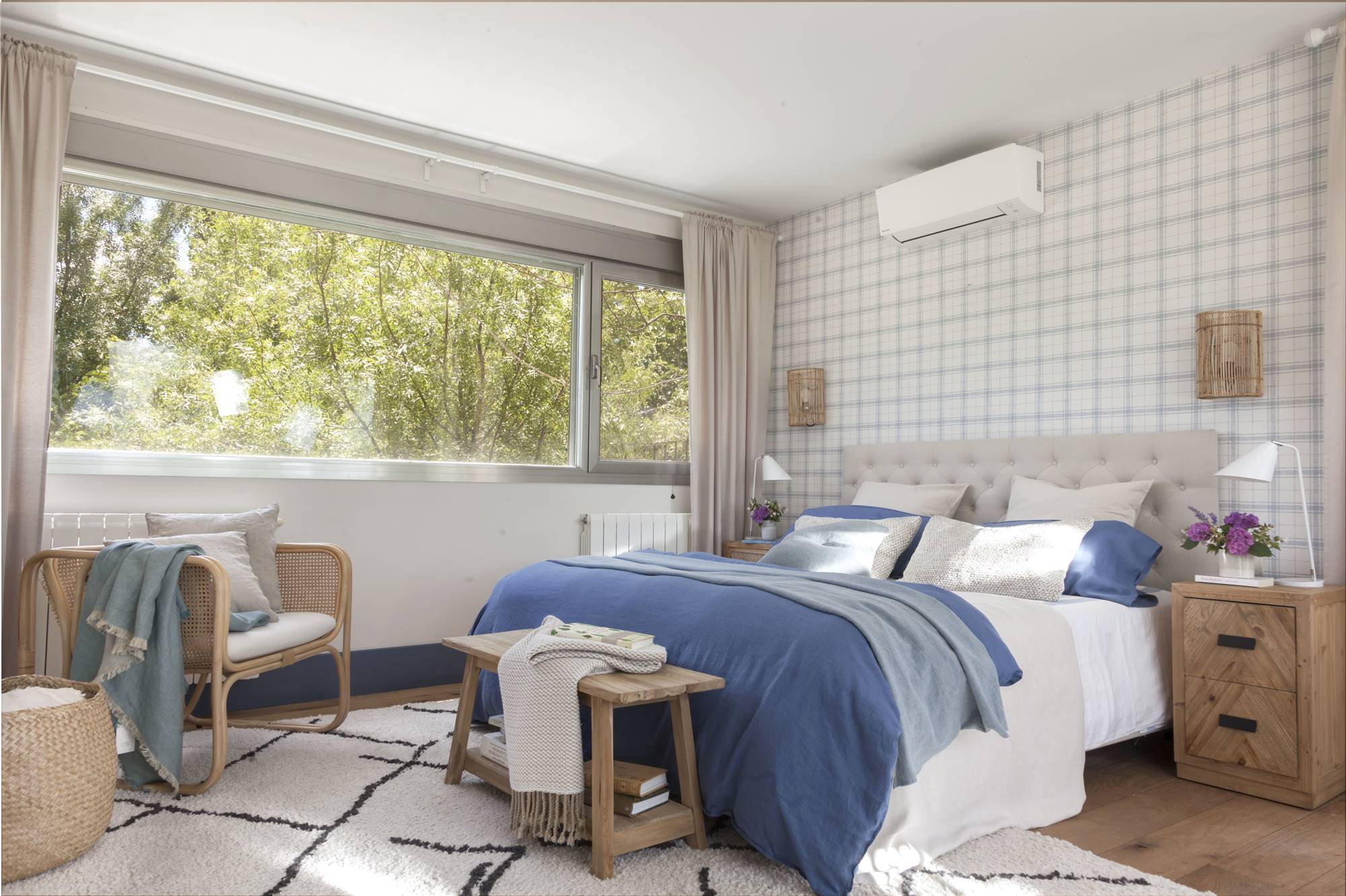 Dormitorio con papel pintado, zócalo azul y aire acondicionado.