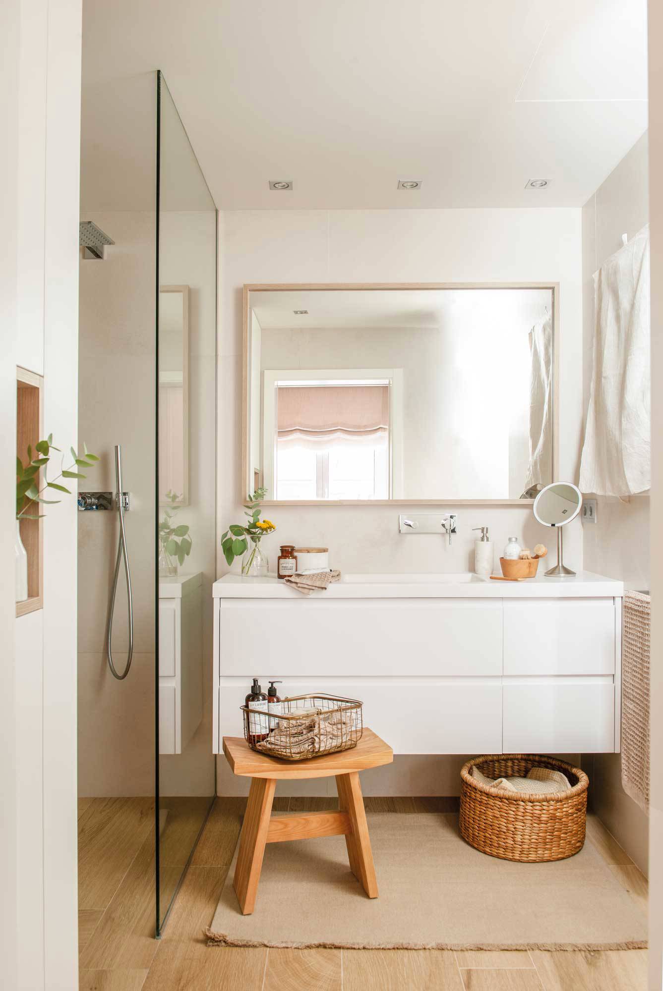 Baño con ducha y mueble blanco volado con lavabo integrado.