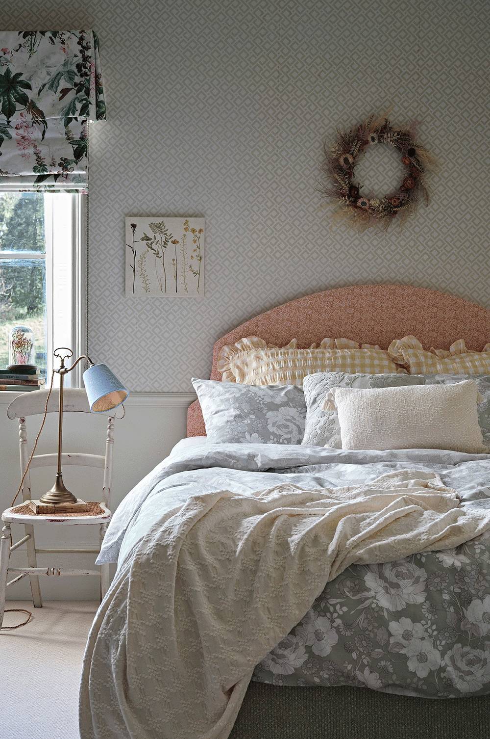Dormitorio con cabecero rosa y ropa de cama floral. 