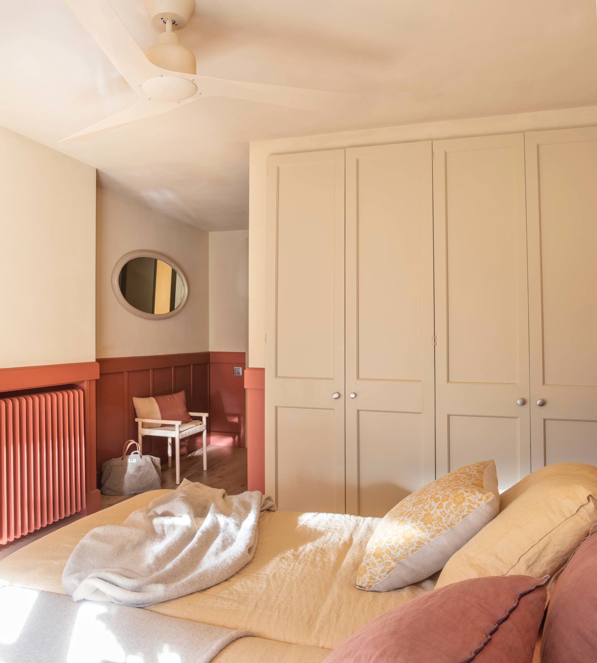 Dormitorio con arrimadero y radiador pintado en color teja. 