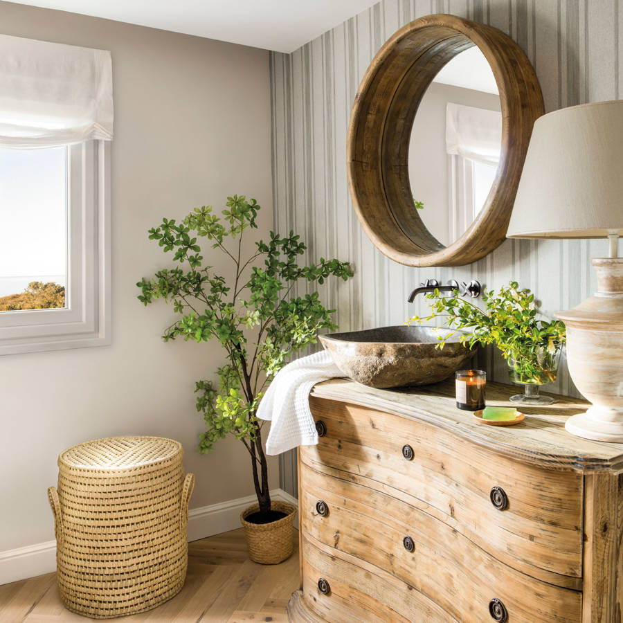Baño con mueble de madera y espejo redondo