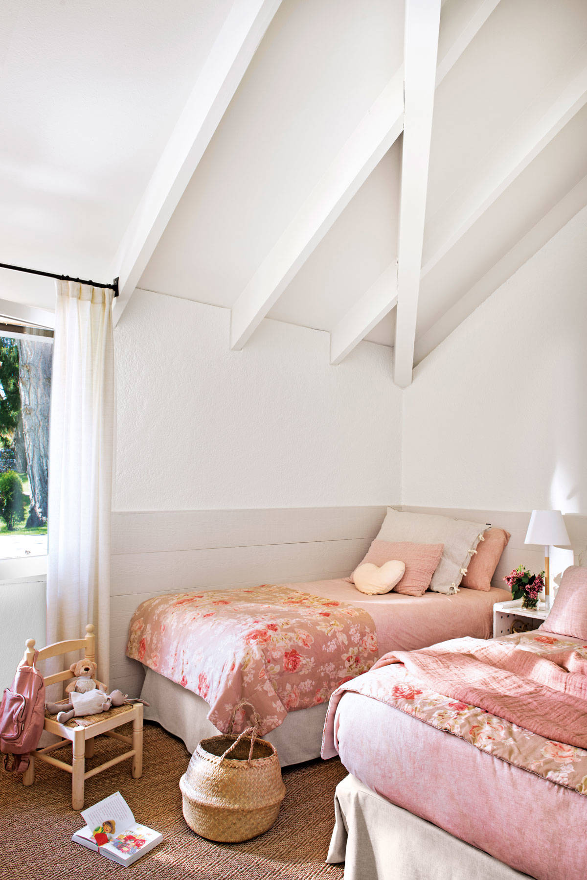 Habitacion infantil con arrimadero, techo abuhardillado y ropa de cama rosa con estampado floral.