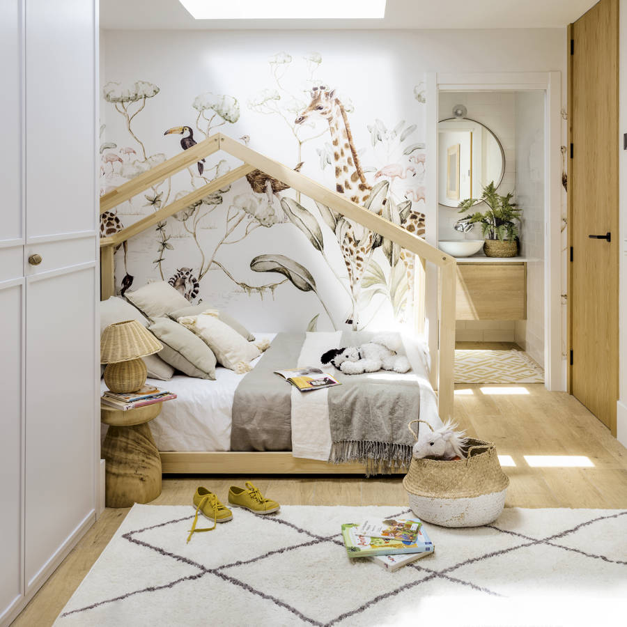 Habitación infantil con cama tipo casita y mural decorativo.