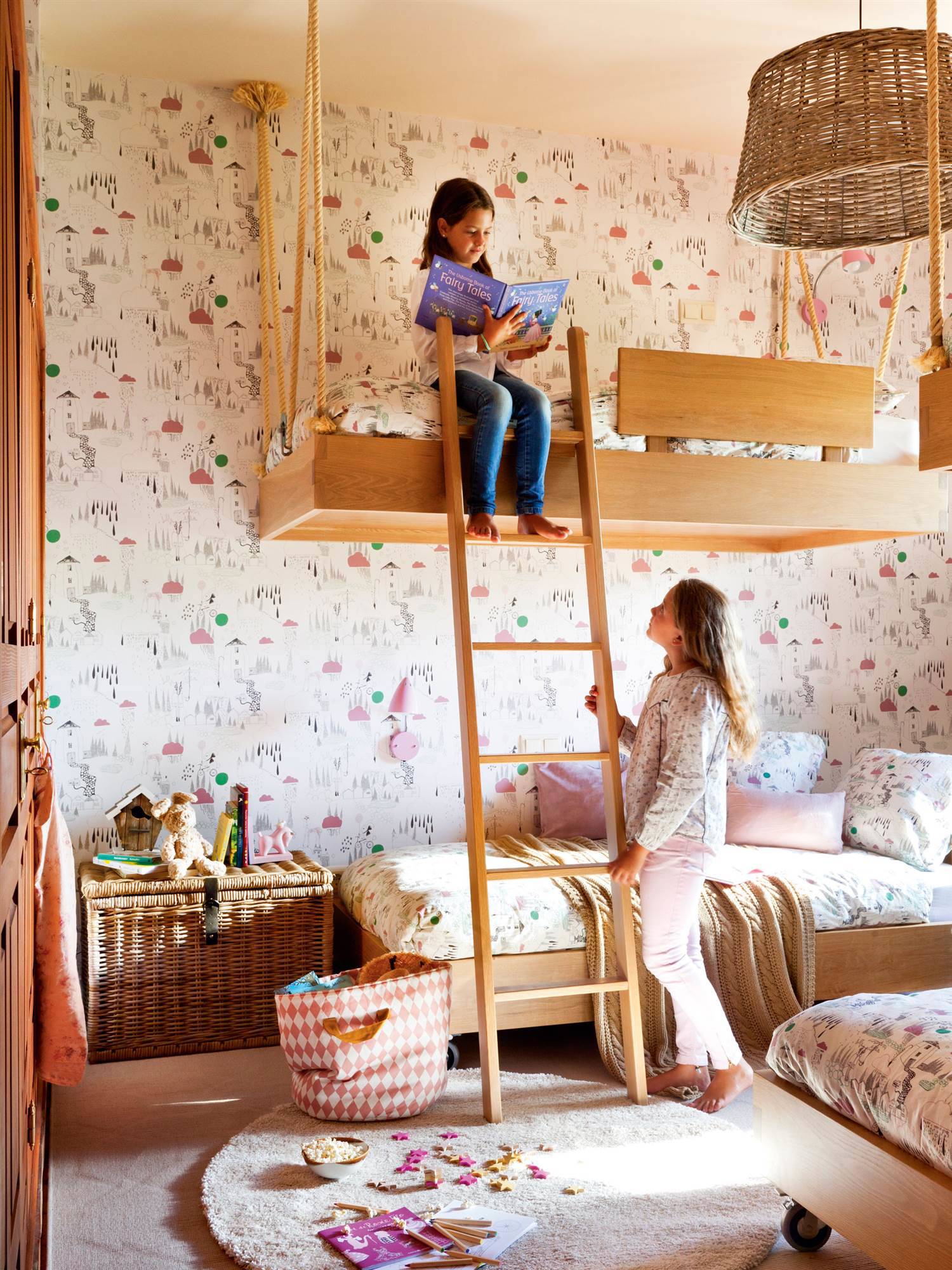 Decoración de dormitorio infantil con literas de madera y papel pintado de fantasía.