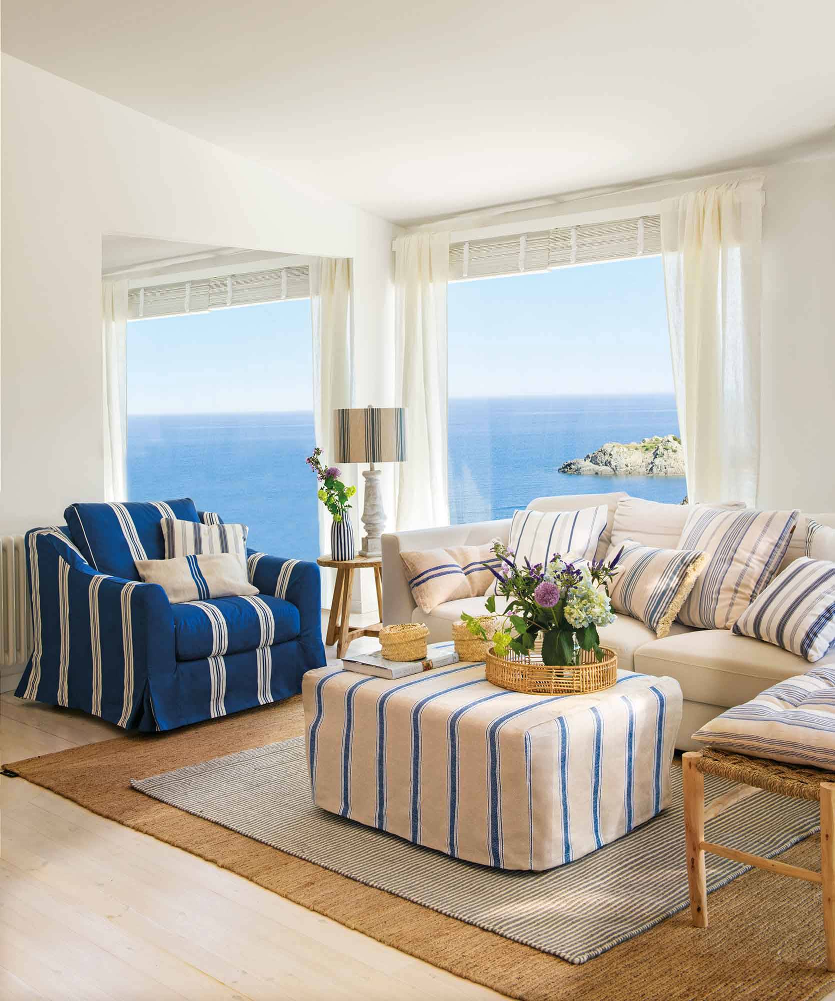 Salón marinero con tapicerías a rayas azules y blancas y vistas al mar.