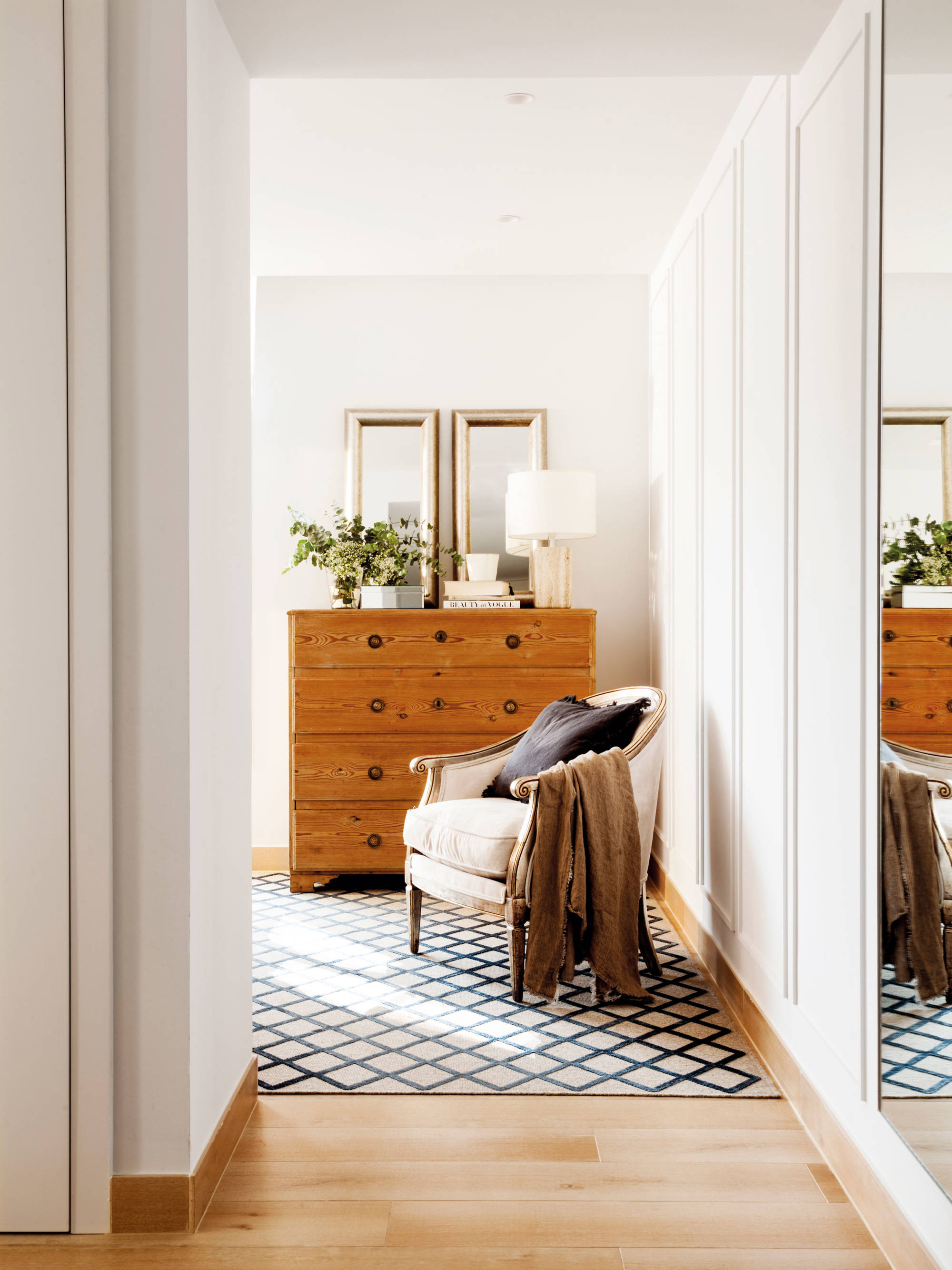 Dormitorio con cómoda de madera y alfombra geométrica. w00521445