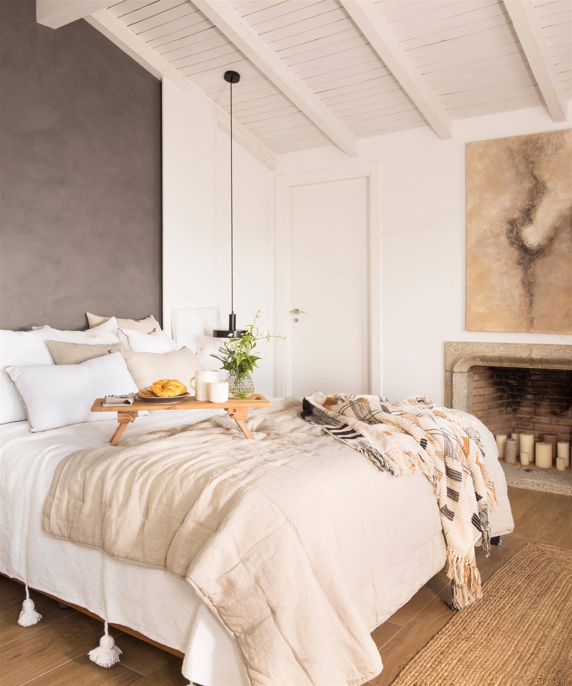Dormitorio con chimenea y cabecero lacado en gris oscuro y cama vestida en blanco
