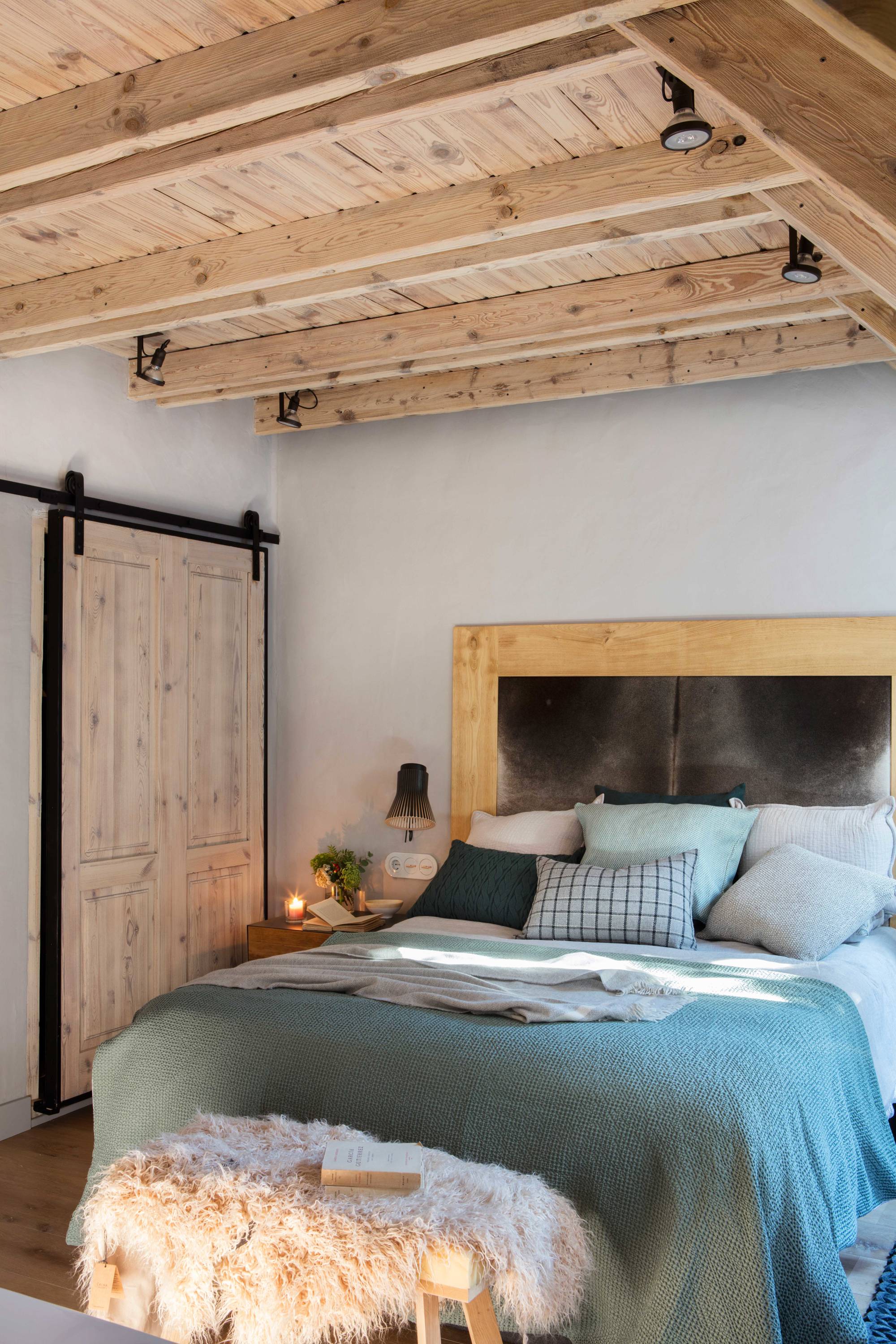 Dormitorio rústico con vigas de maderaa y puerta corredera tipo granero