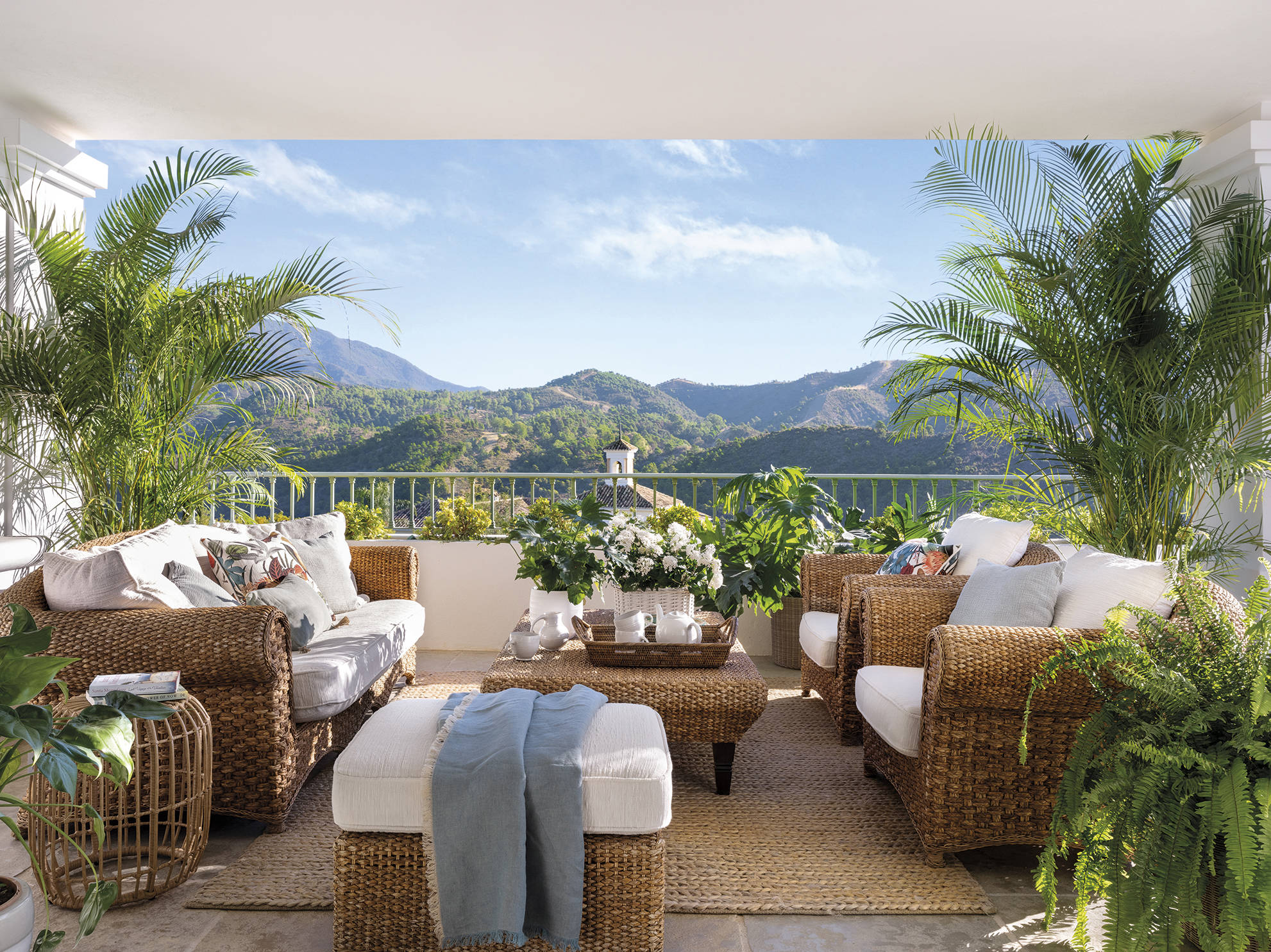 Terraza decorada con muebles de fibras y vistas a las montañas