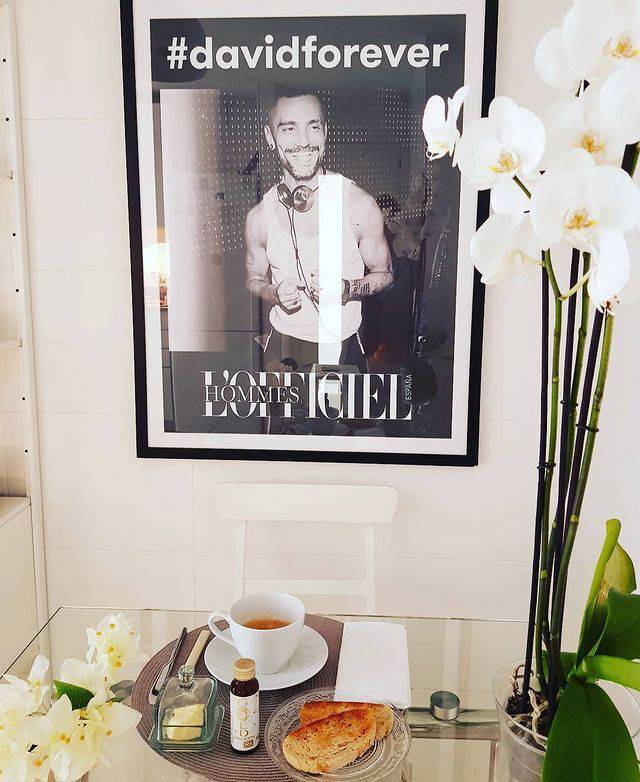 Cocina con mesa de cristal, flores blancas y un cuadro con la fotografía de David Delfín