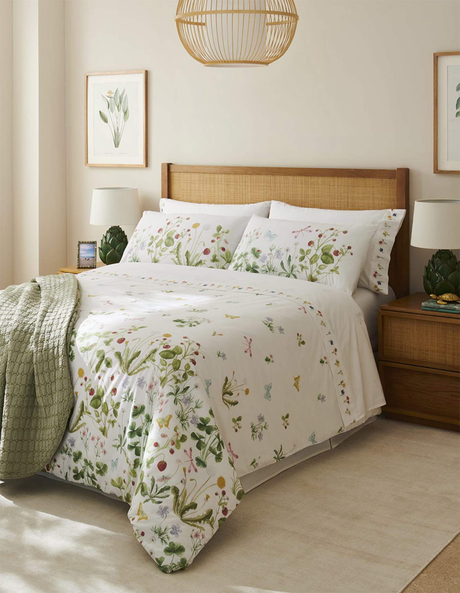 Dormitorio con ropa de cama floral y cabecero de madera y fibras.