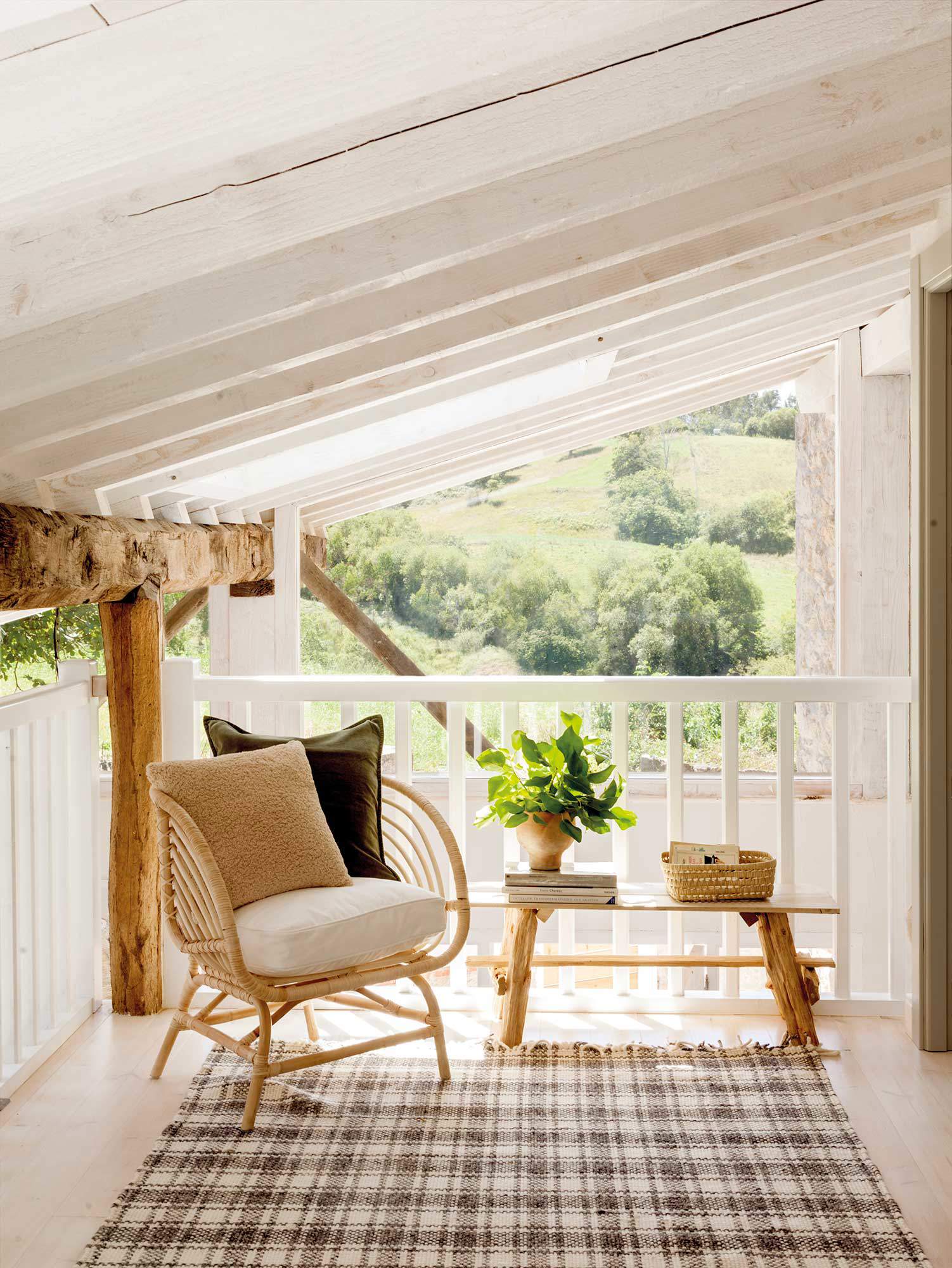 Terraza con sillón de fibra natural y alfombra de cuadros.