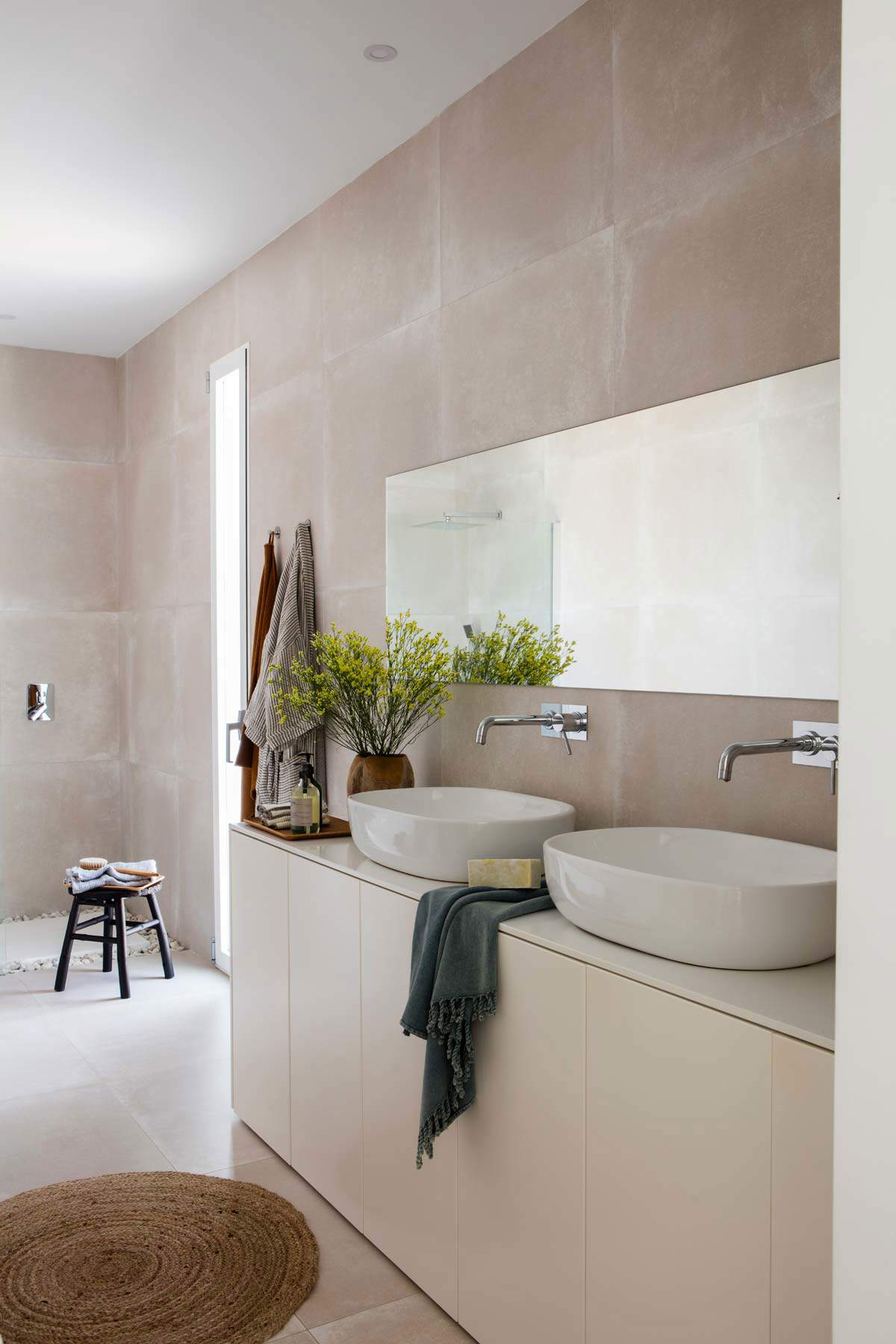 Baño minimalista con mueble de color topo y espejo rectangular sin marco. 